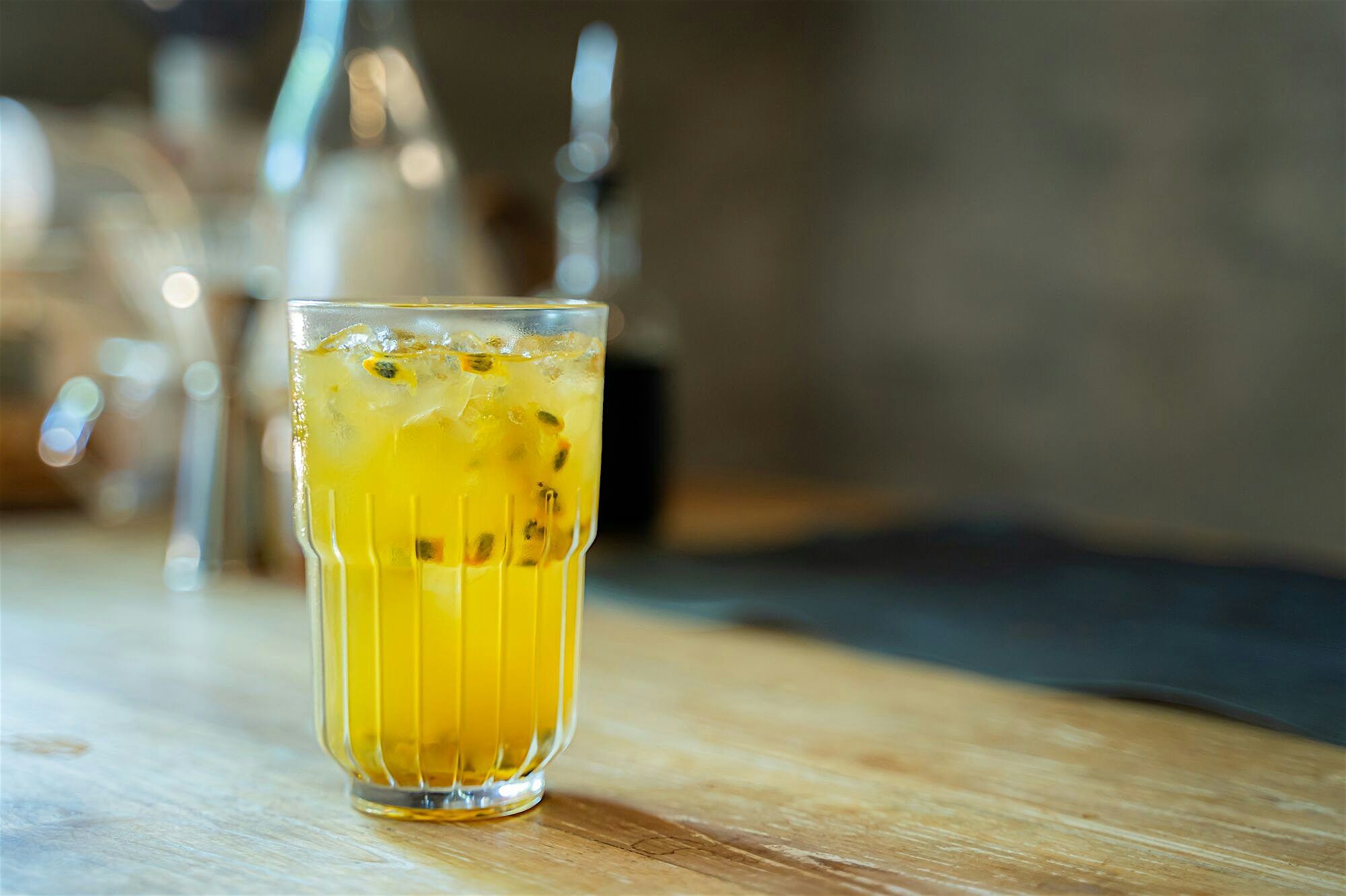 Passion fruit lemonade with ice in a tall glass on a wooden bar