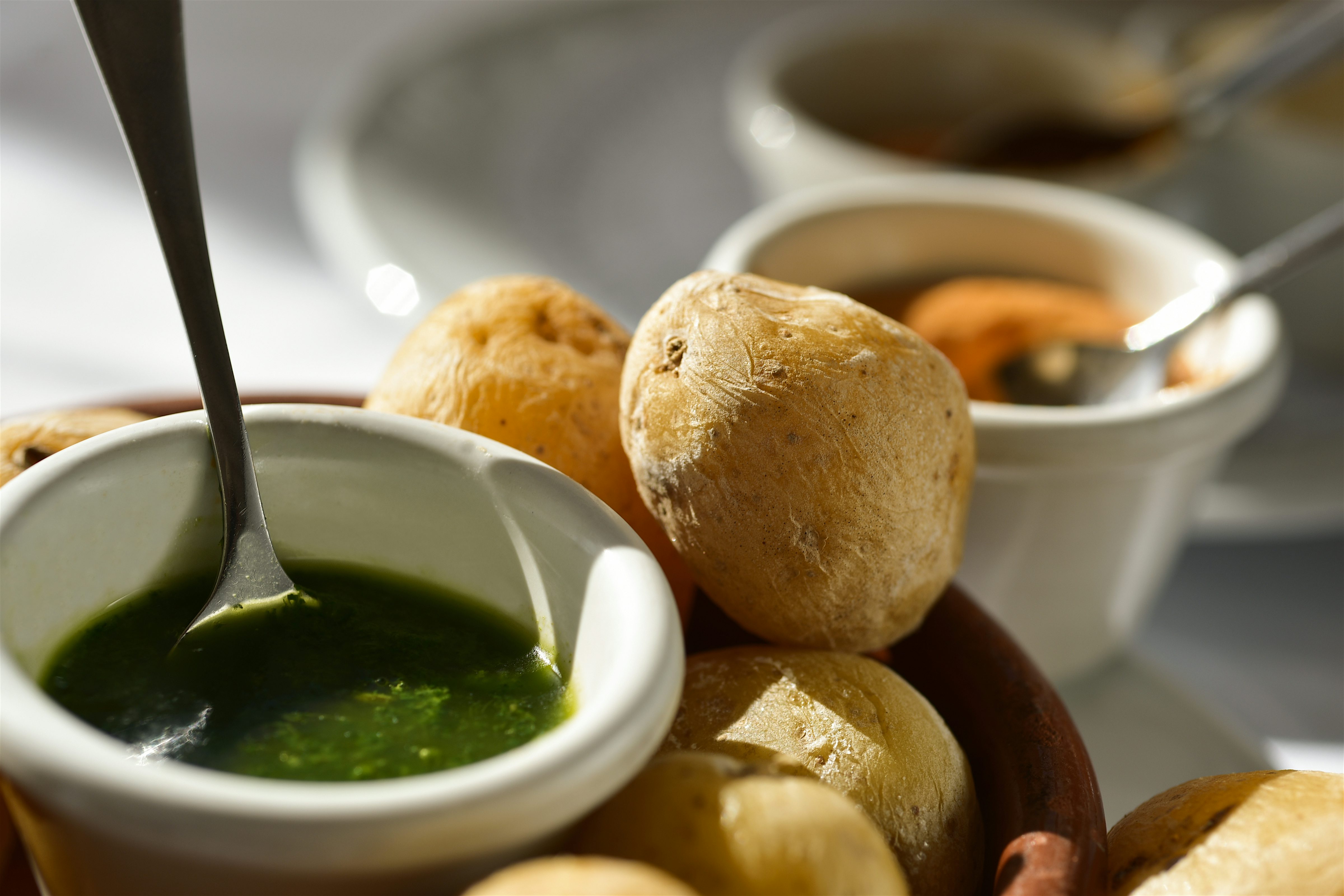Papas arrugadas (wrinkled potatoes) in a dish with Mojo verde (green sauce) and Mojo rojo (red sauce) in small bowls.