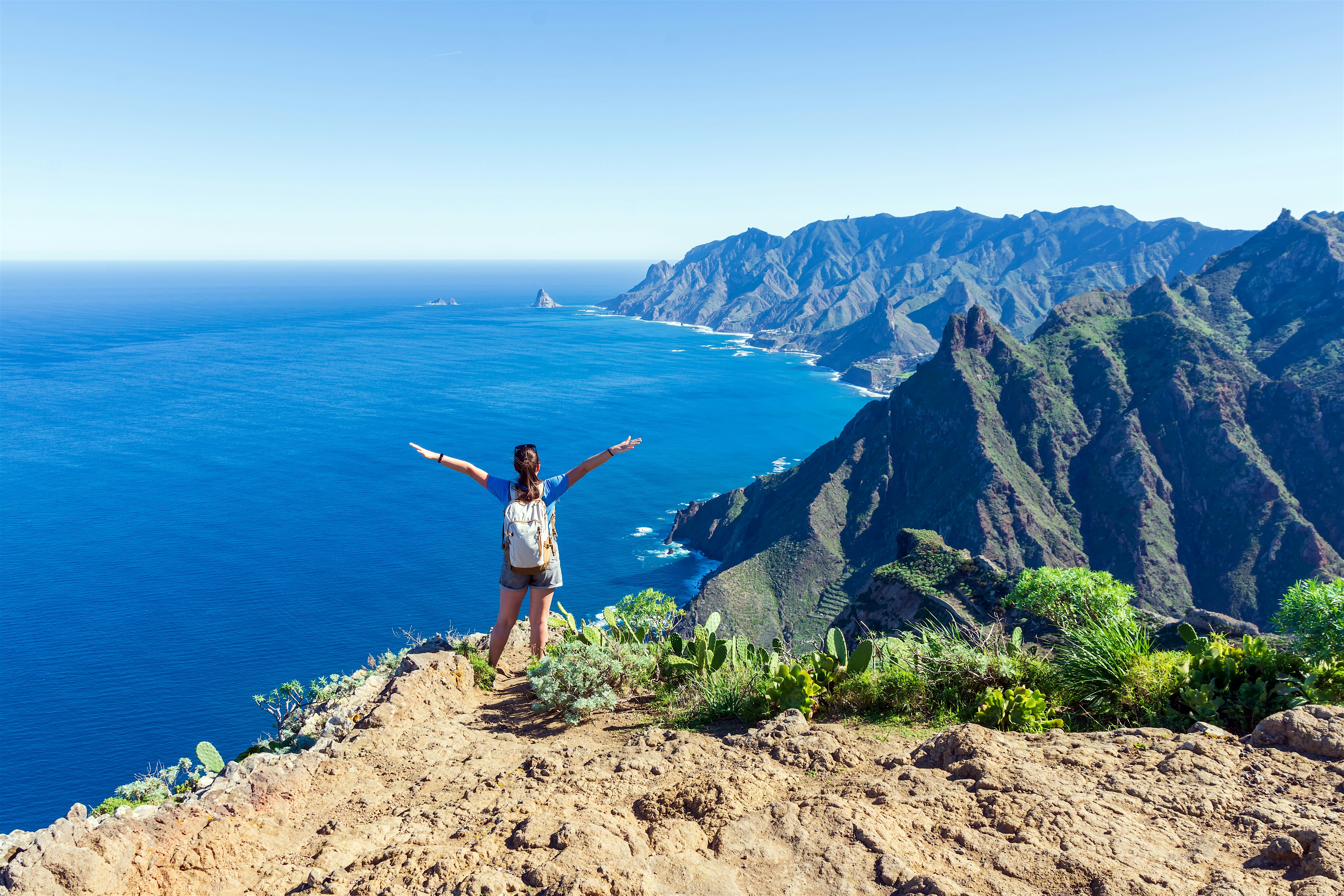 Anaga Rural Park. Hiker at the top of a mountain looking out to the ocean and the other peaks in the distance