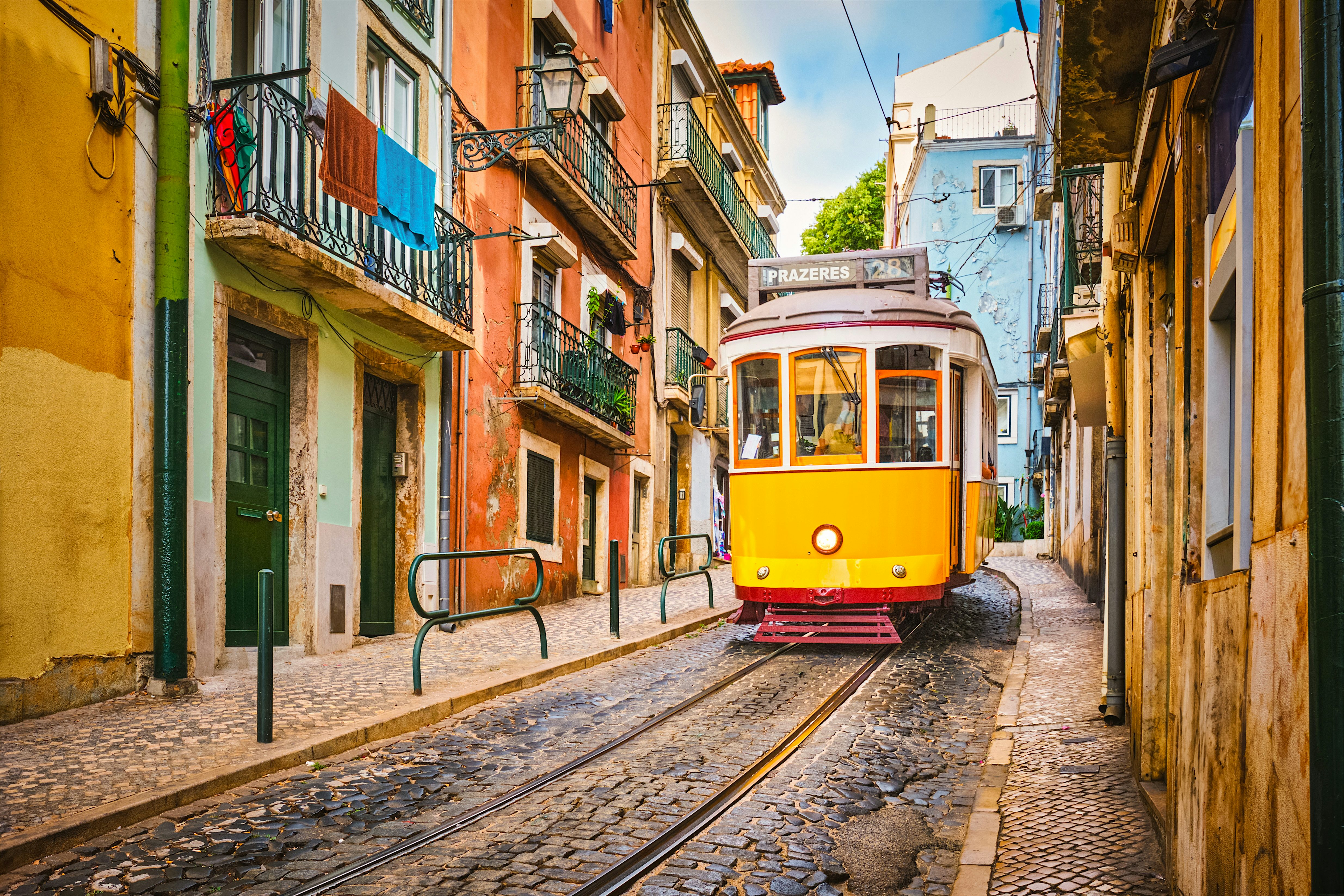 Yellow tram travelling along narrow cobbled tracks through a steep city street