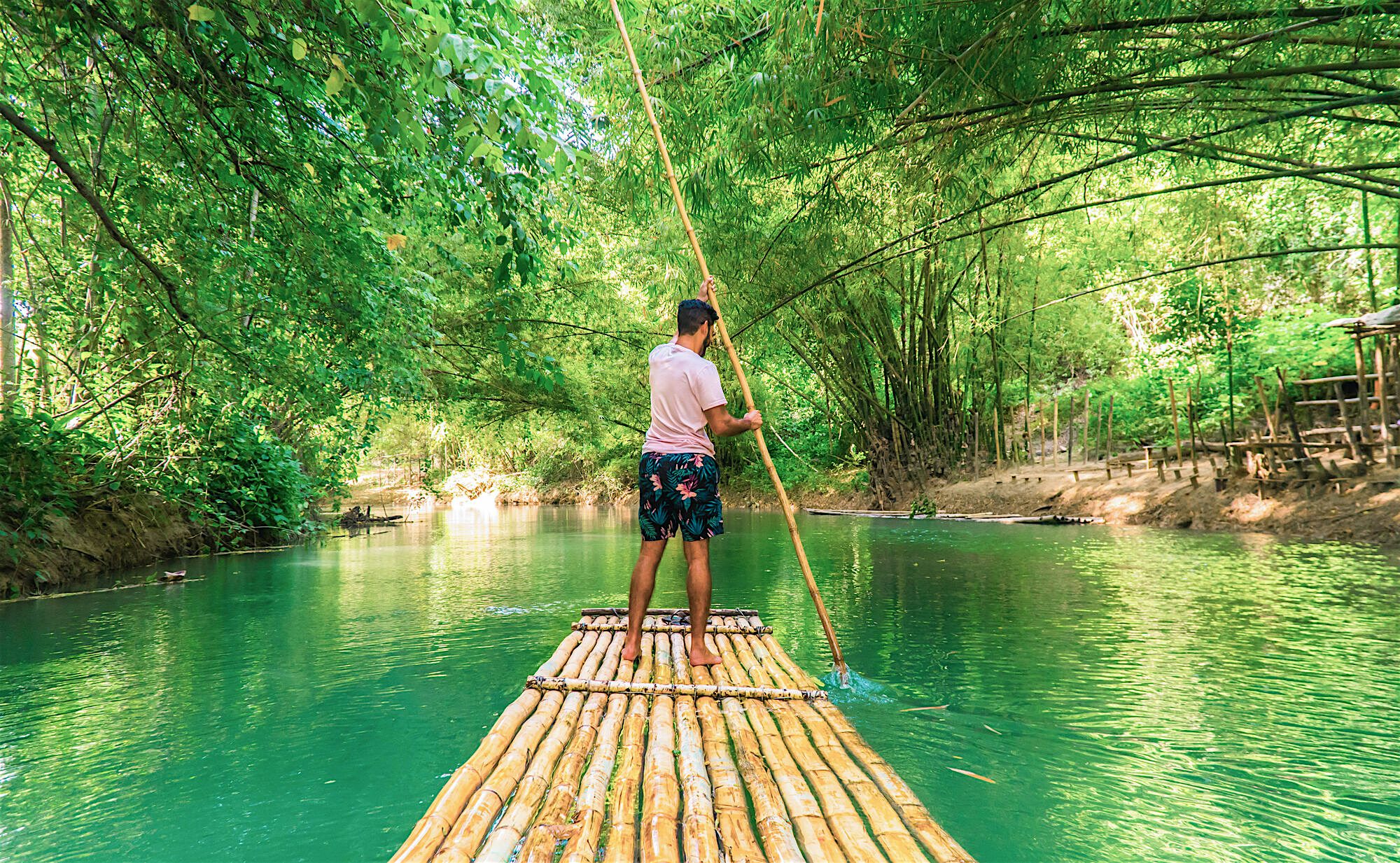 River rafting tour. Man using a long pole on traditional 30-foot bamboo raft.