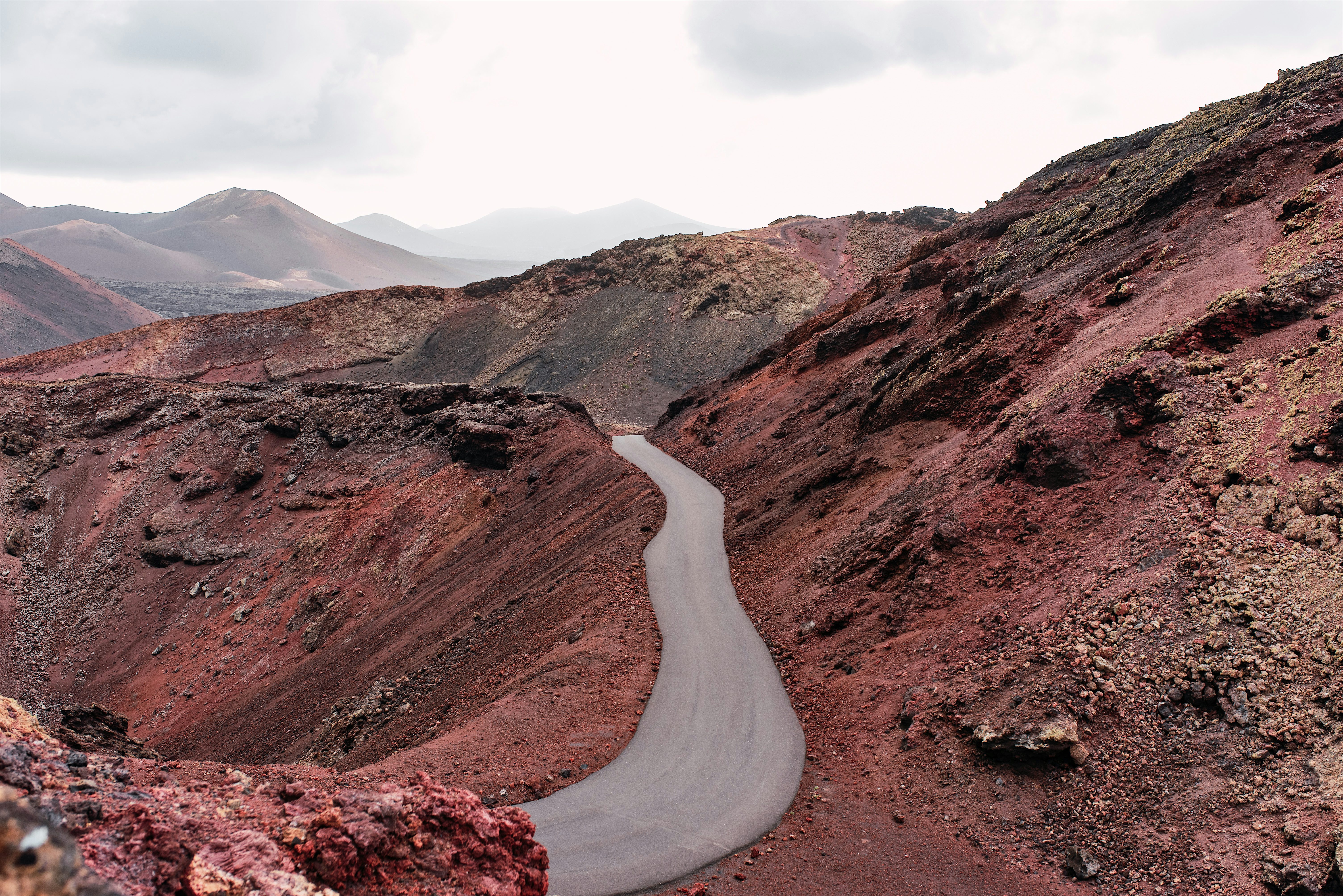 Narrow road winding through the red volcanic landscape of Timanfaya National Park