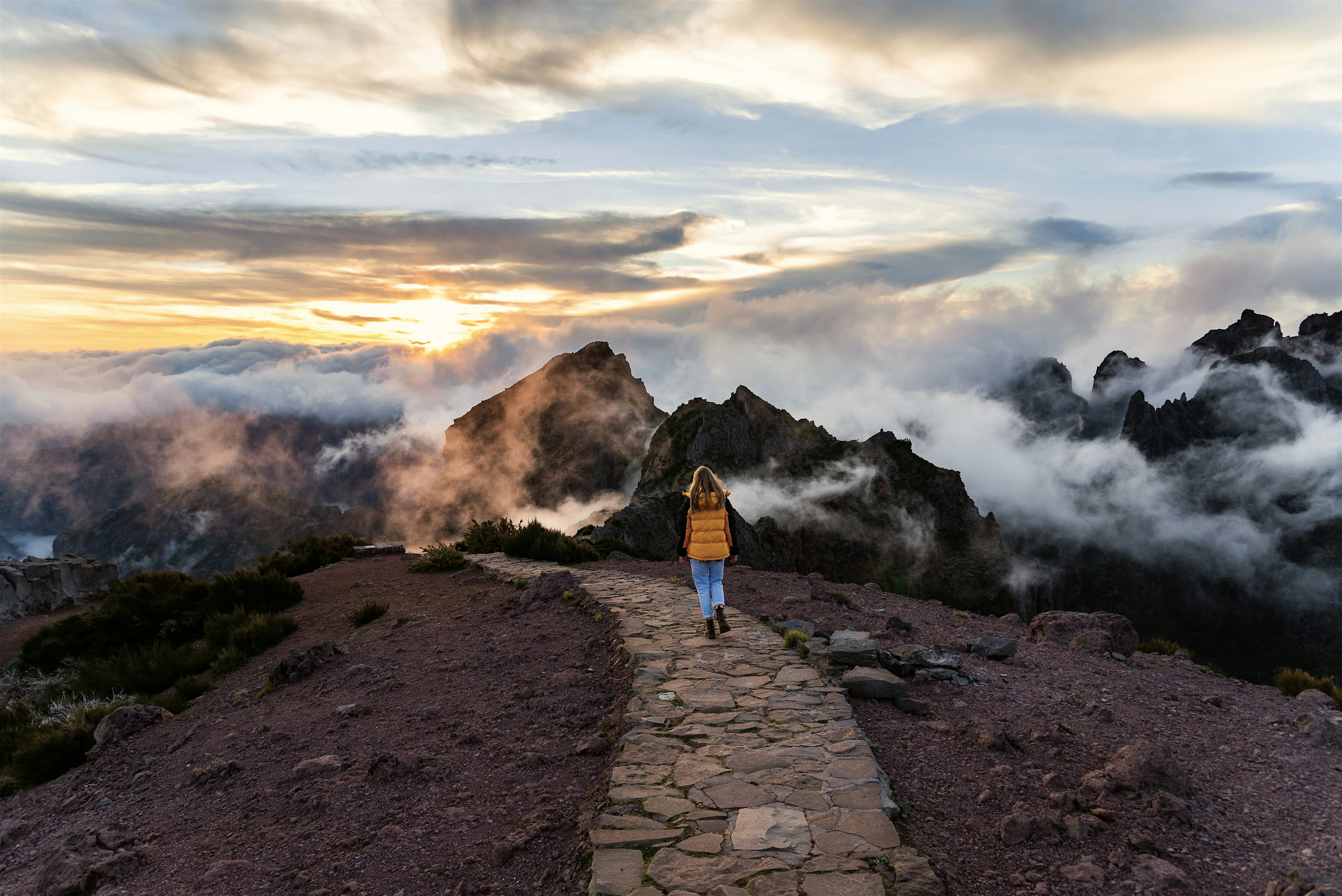 Person on a sunset hike high above the clouds in the volcanic mountains