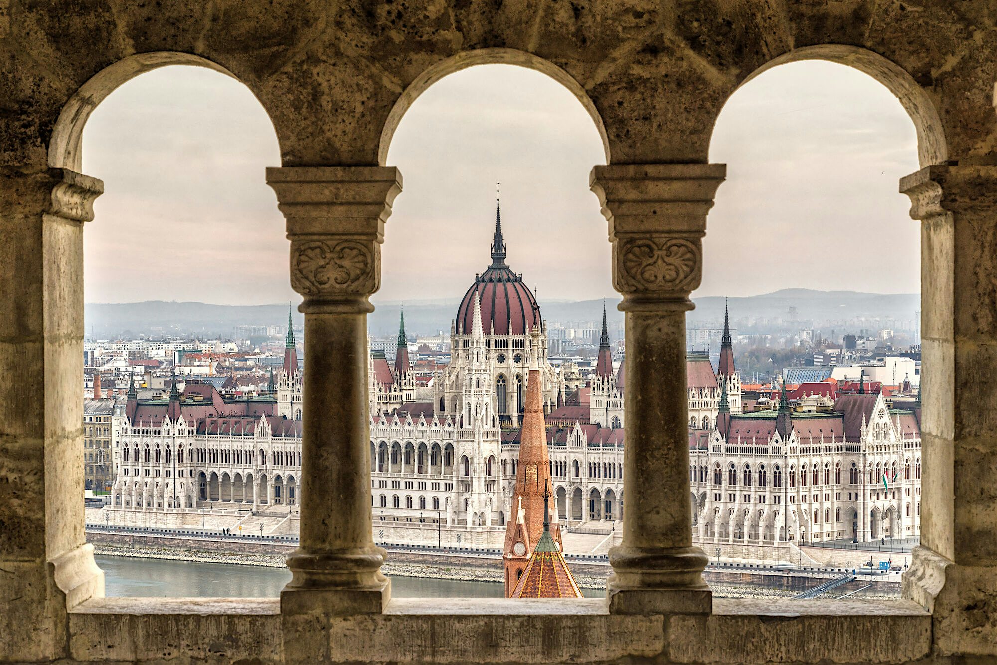 View through three stone arches framing the Hungarian Parliament Building in Budapest