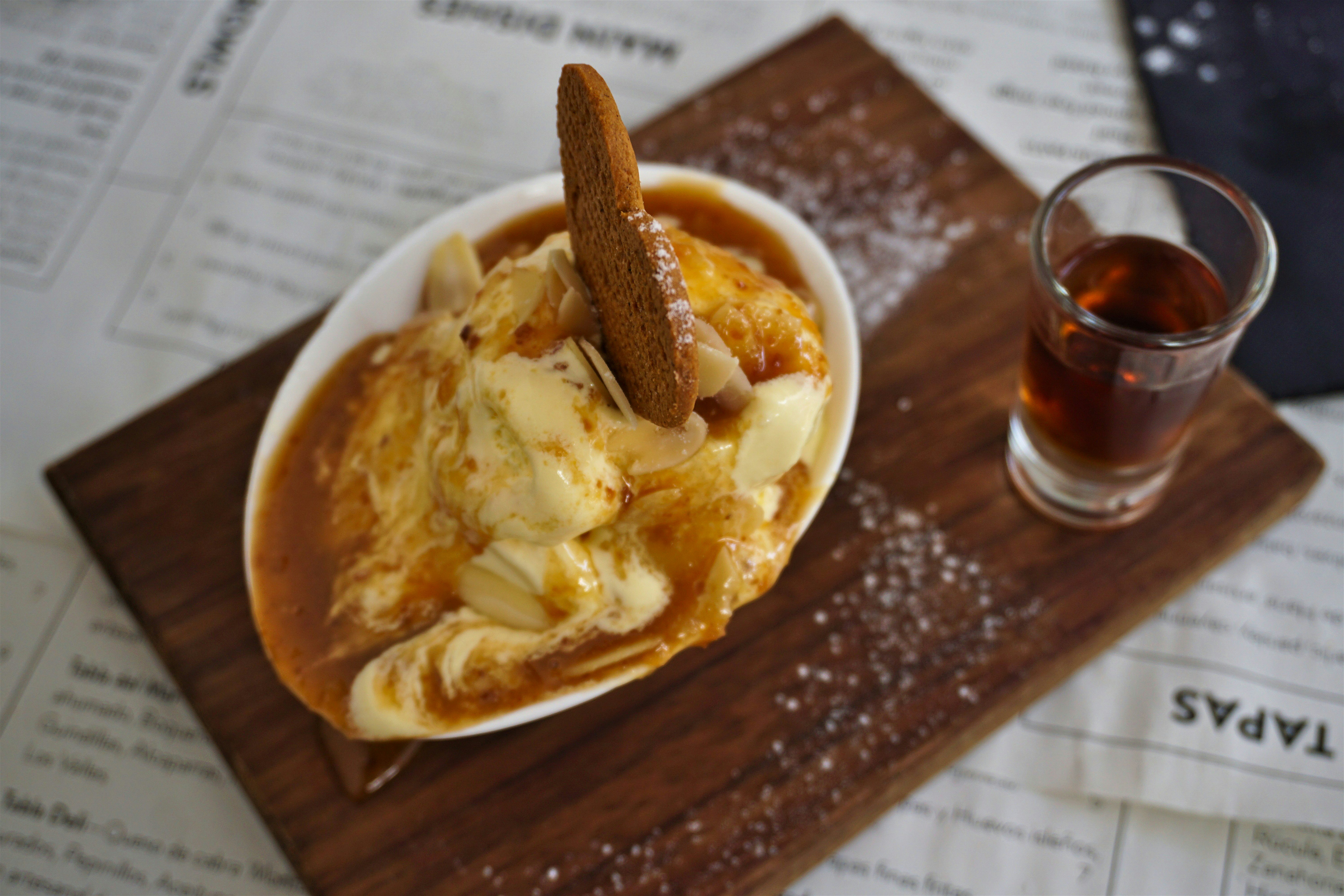 Bienmesabe, a traditional dessert garnished with a biscuit and a small glass of liqueur.