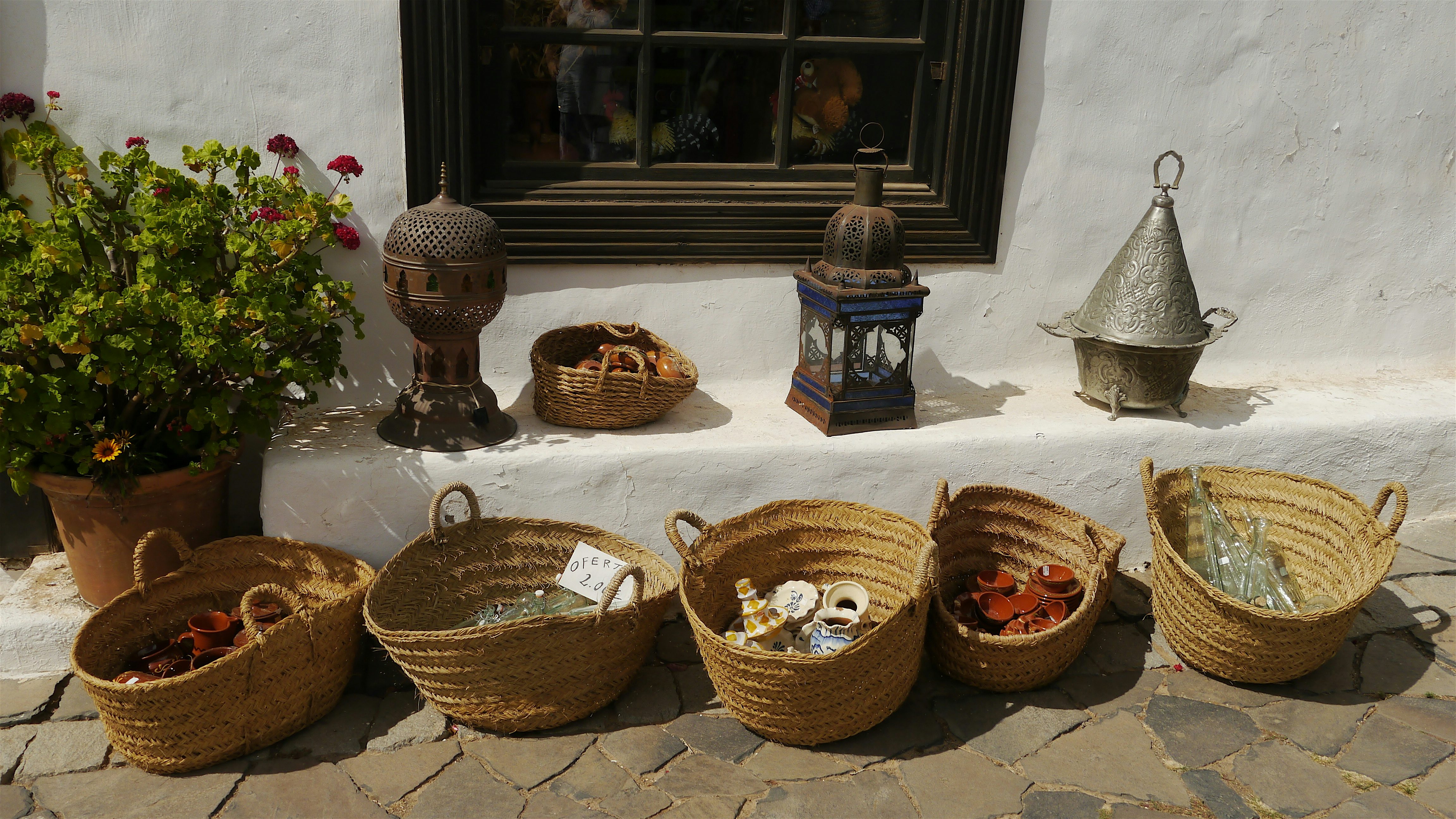 Traditional, handmade wicker baskets containing souvenirs displayed outside a whitewashed building