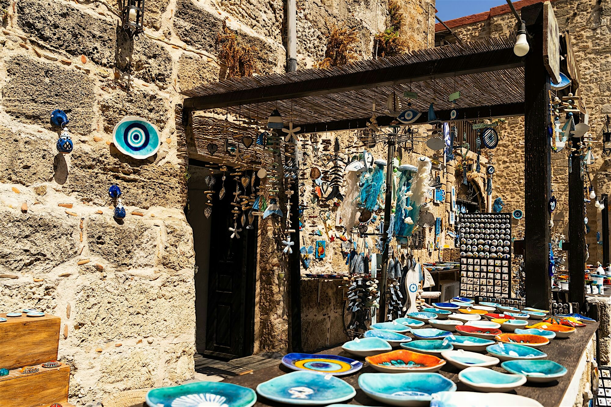 Historic stone building exterior displaying handcrafted Greek ceramics and traditional souvenirs