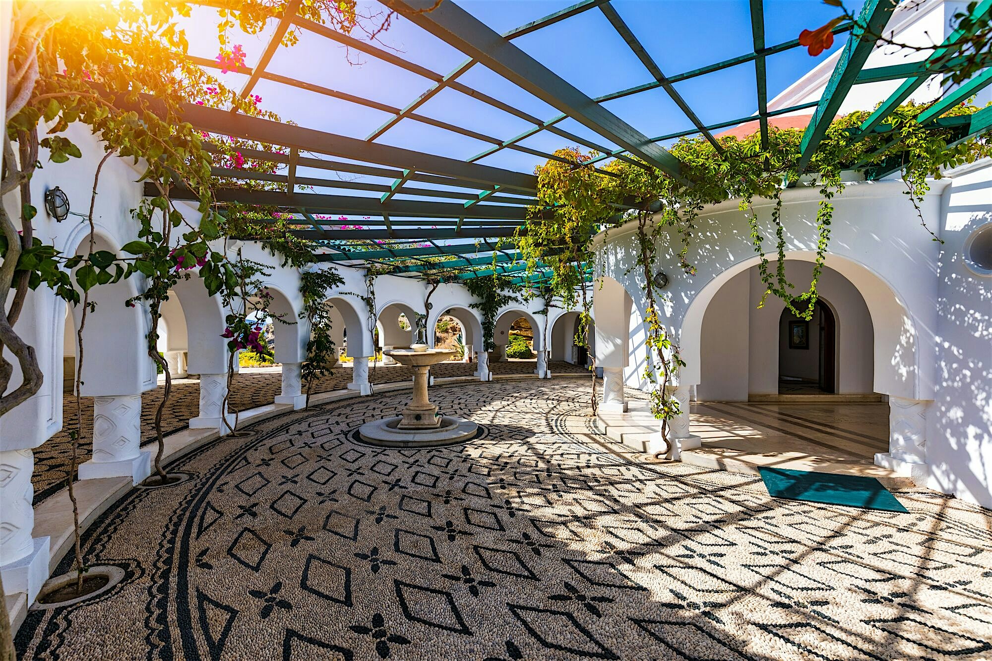 Kallithea Springs white arched walkways, mosaic pebble floors, fountain, green vines