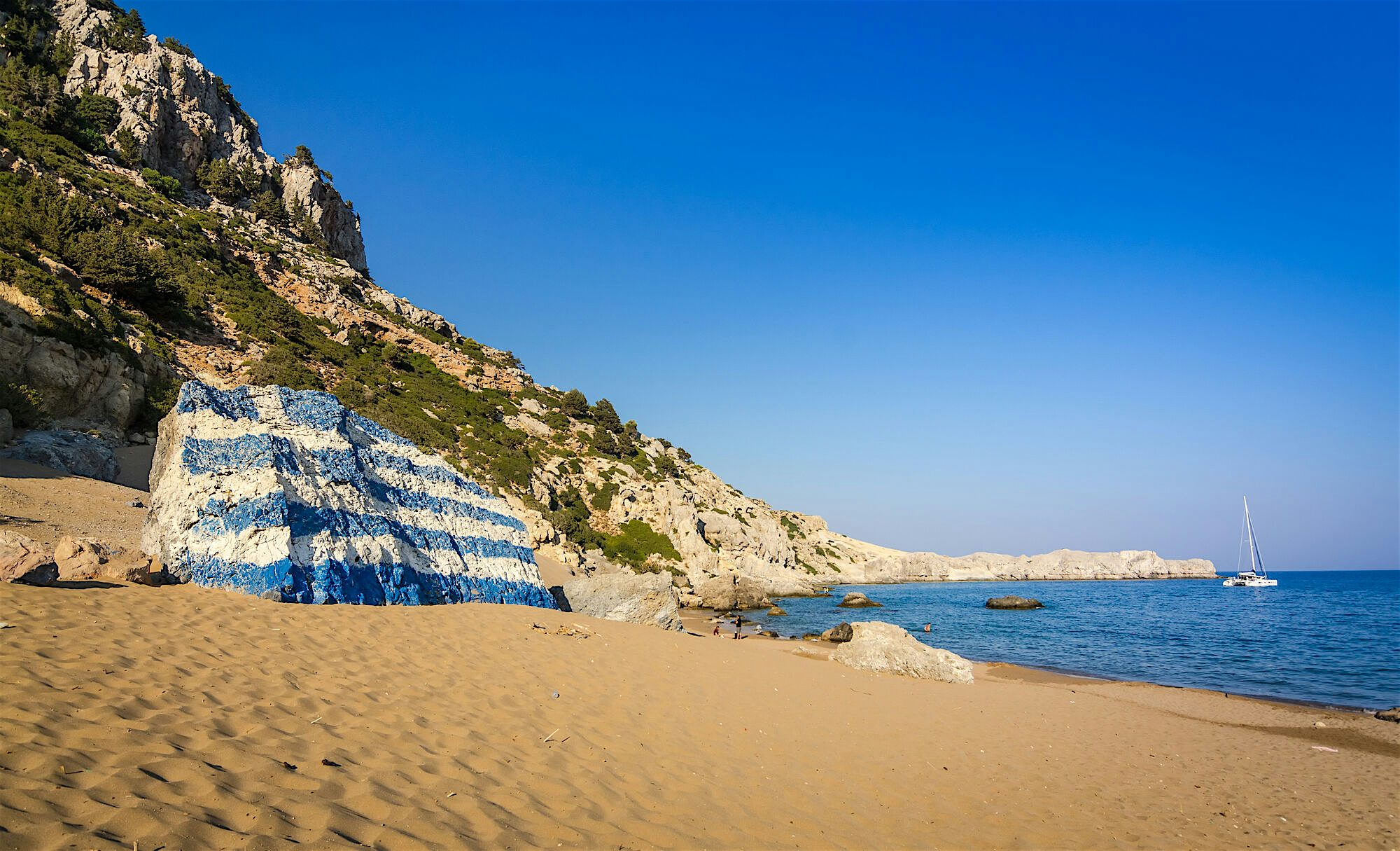 Tsambika Beach large rock on the left is painted with the Greek flag