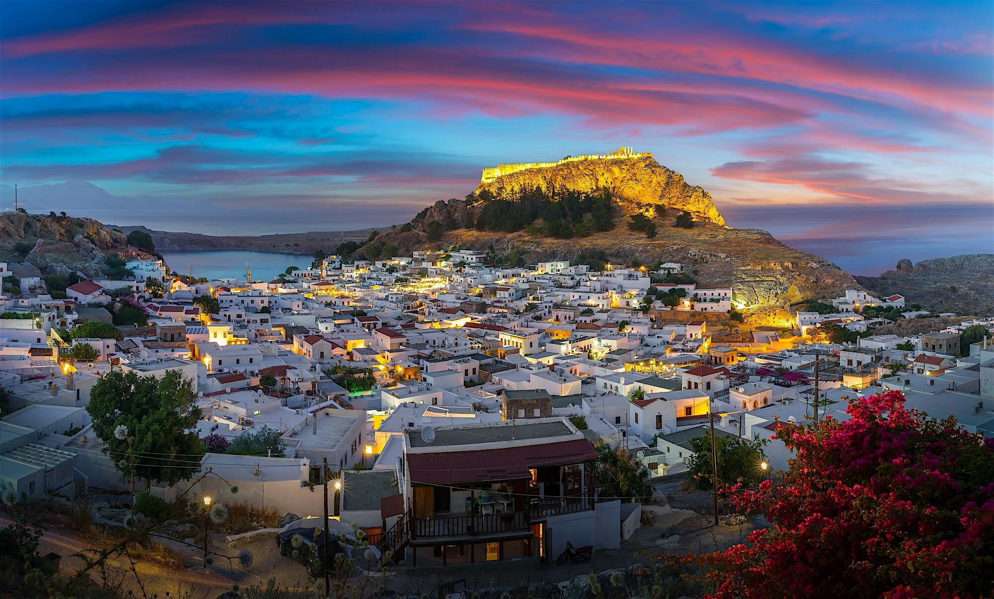 Sunset over the Acropolis of Lindos above the village with lit up whitewashed houses