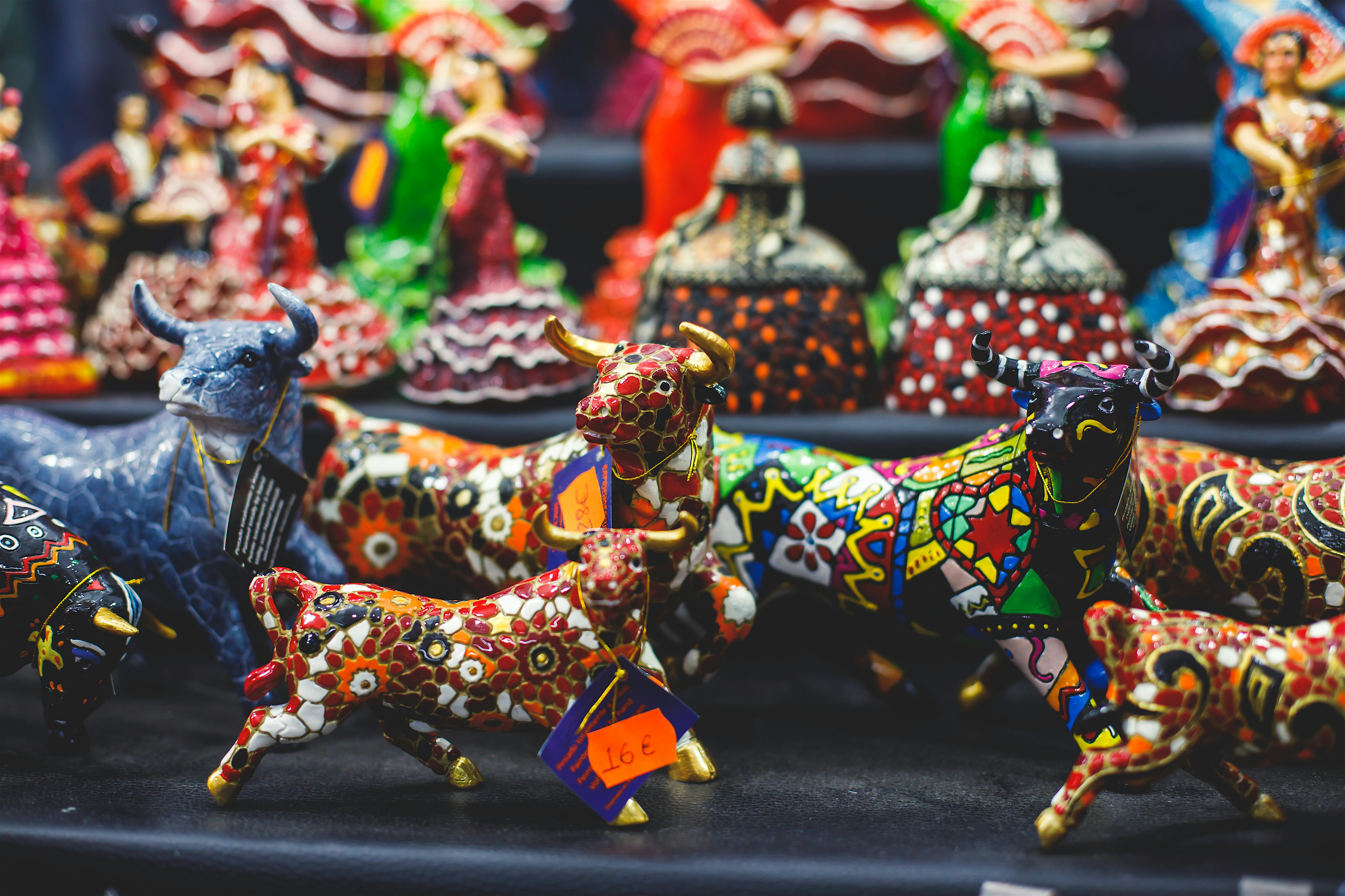 Colourful ceramic animal figurines displayed on a market stall, decorated with intricate patterns and bright painted details.