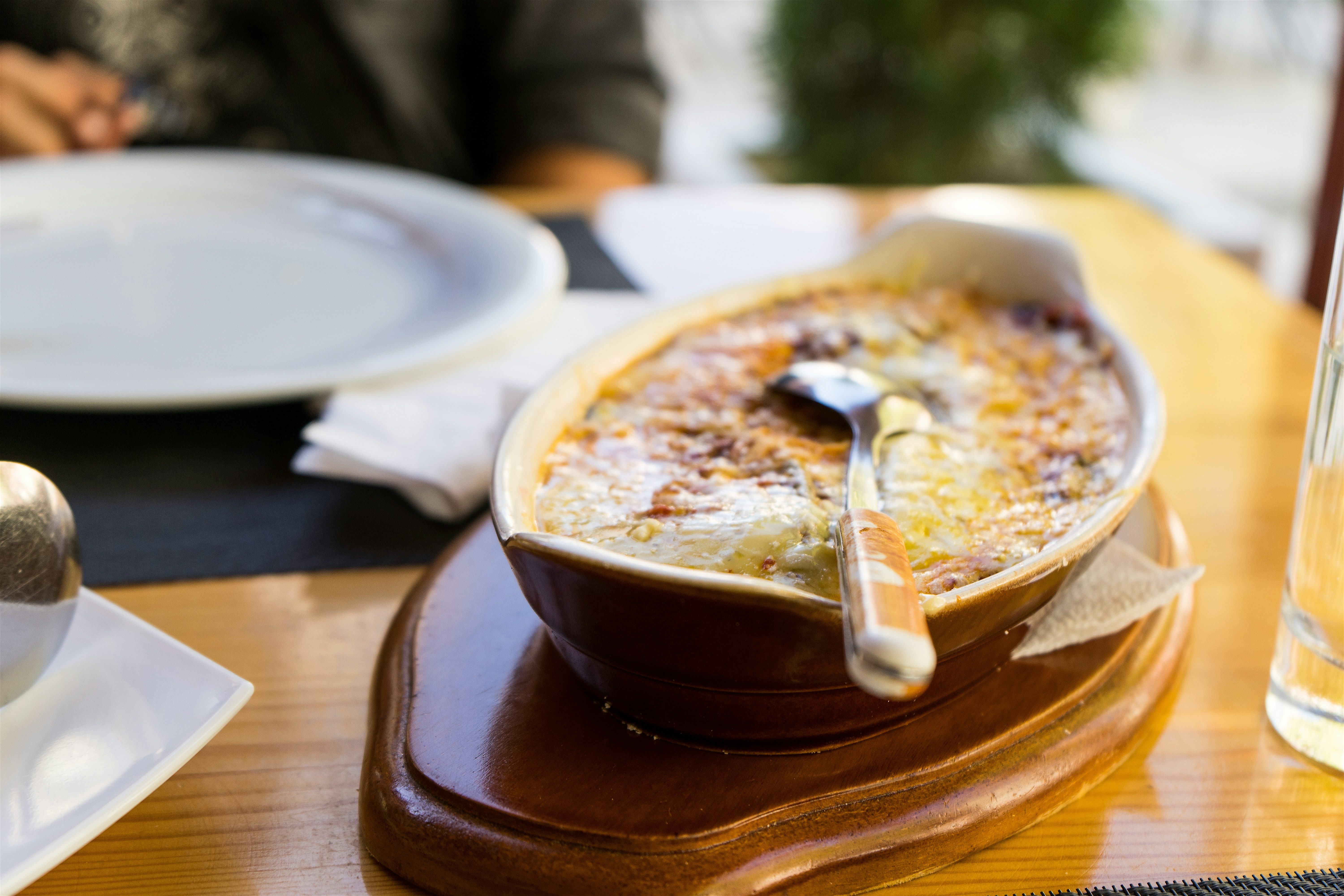 Ceramic dish of Tavë Kosi a traditional Albanian baked dish on a wooden table.
