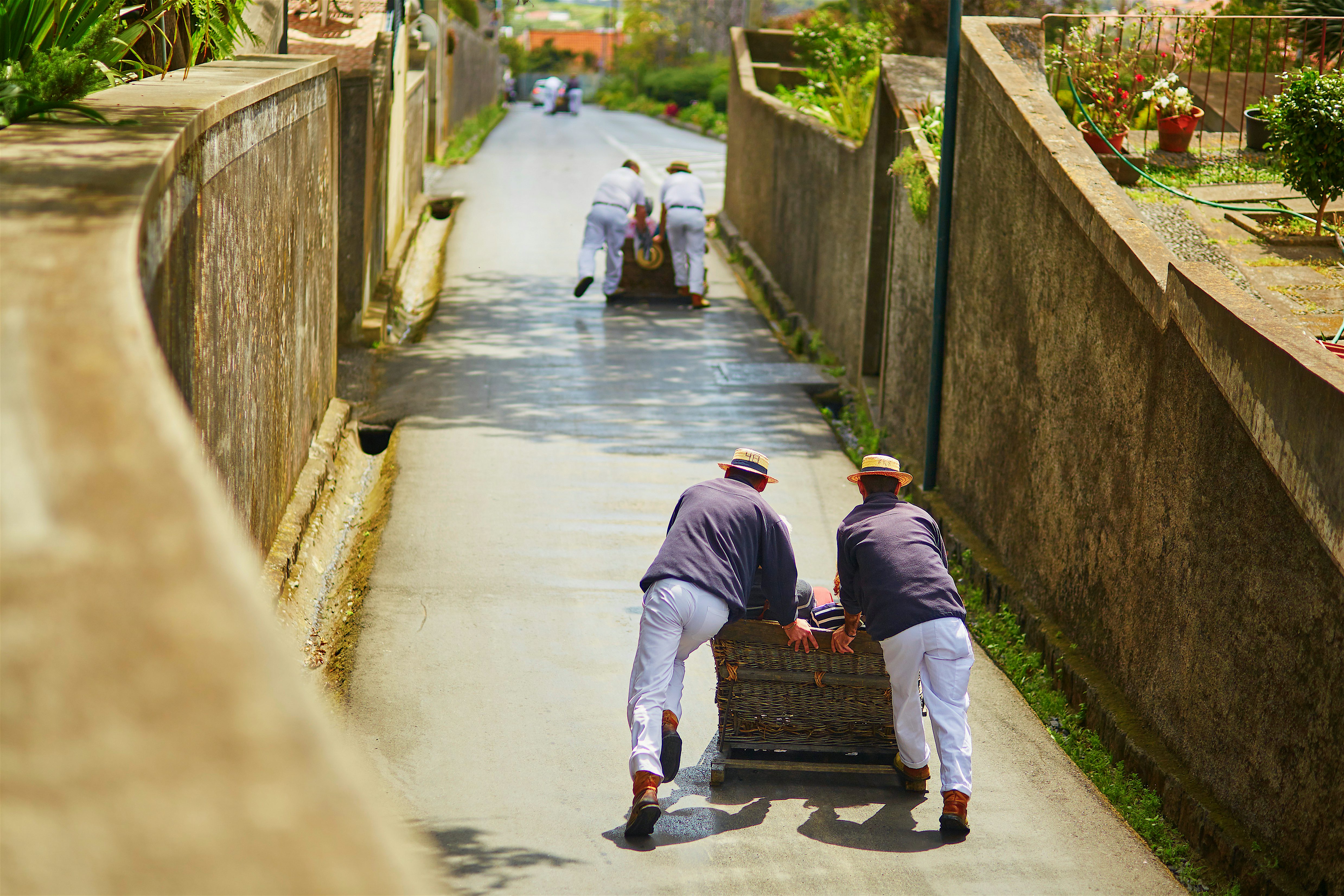 Traditional Monte Toboggan Run in Funchal wicker basket sledges steered and pushed by two carreiros dressed in traditional uniforms and straw hats.