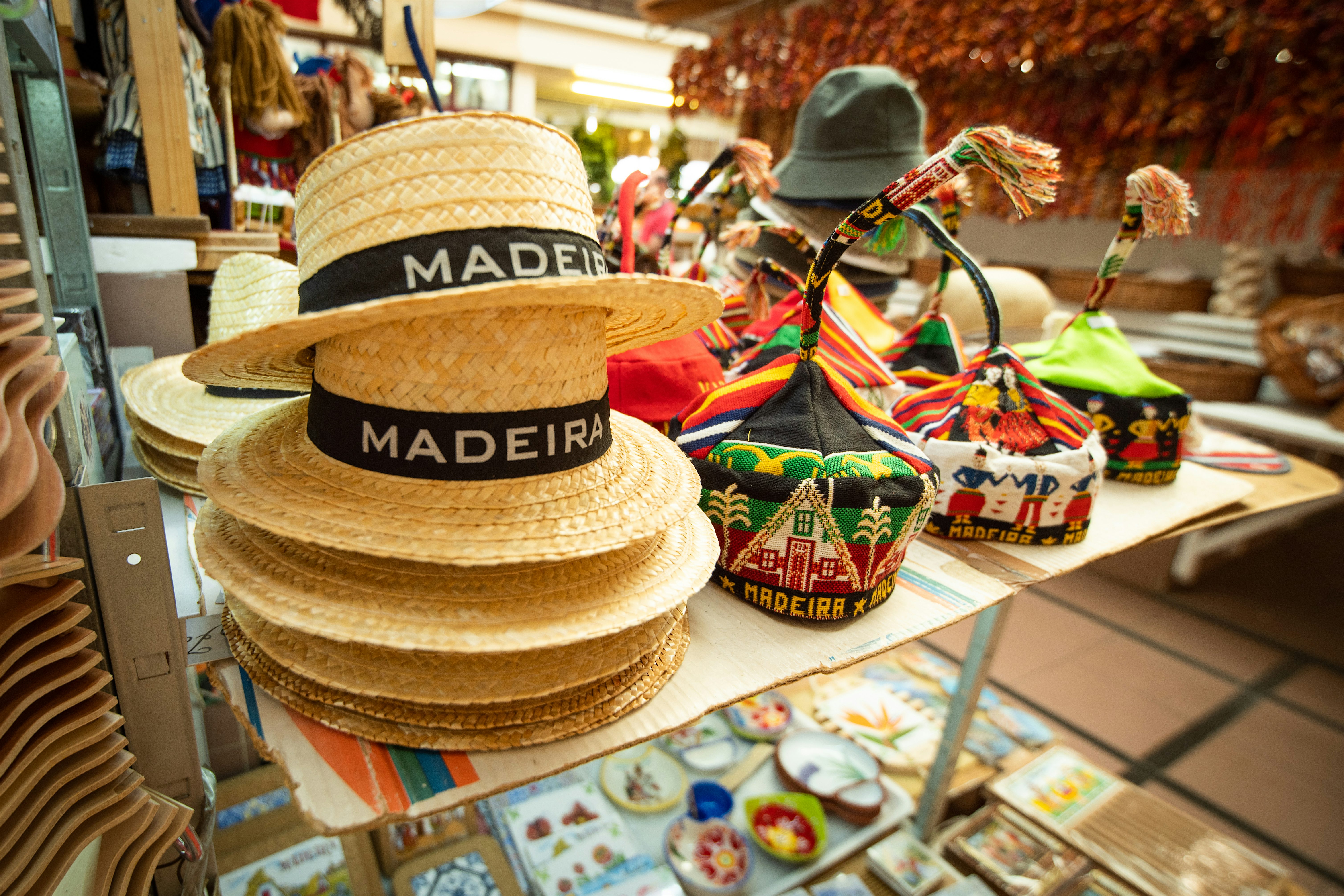 Market table displaying traditional Madeiran wool hats with long tails and patterned straw hats