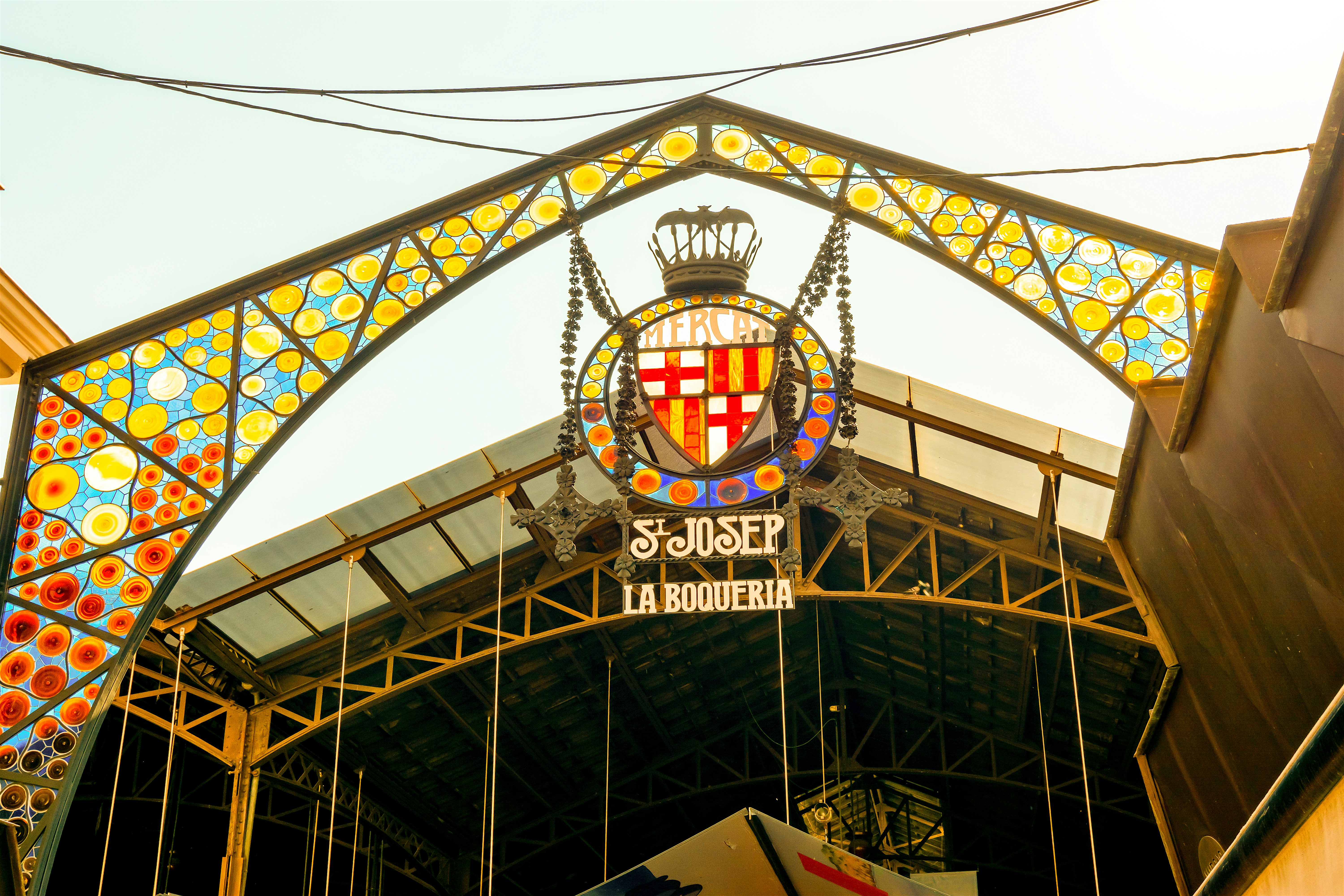 Entrance sign to a food market 'La Boqueria'. The sign is bright colourful patterned stained glass