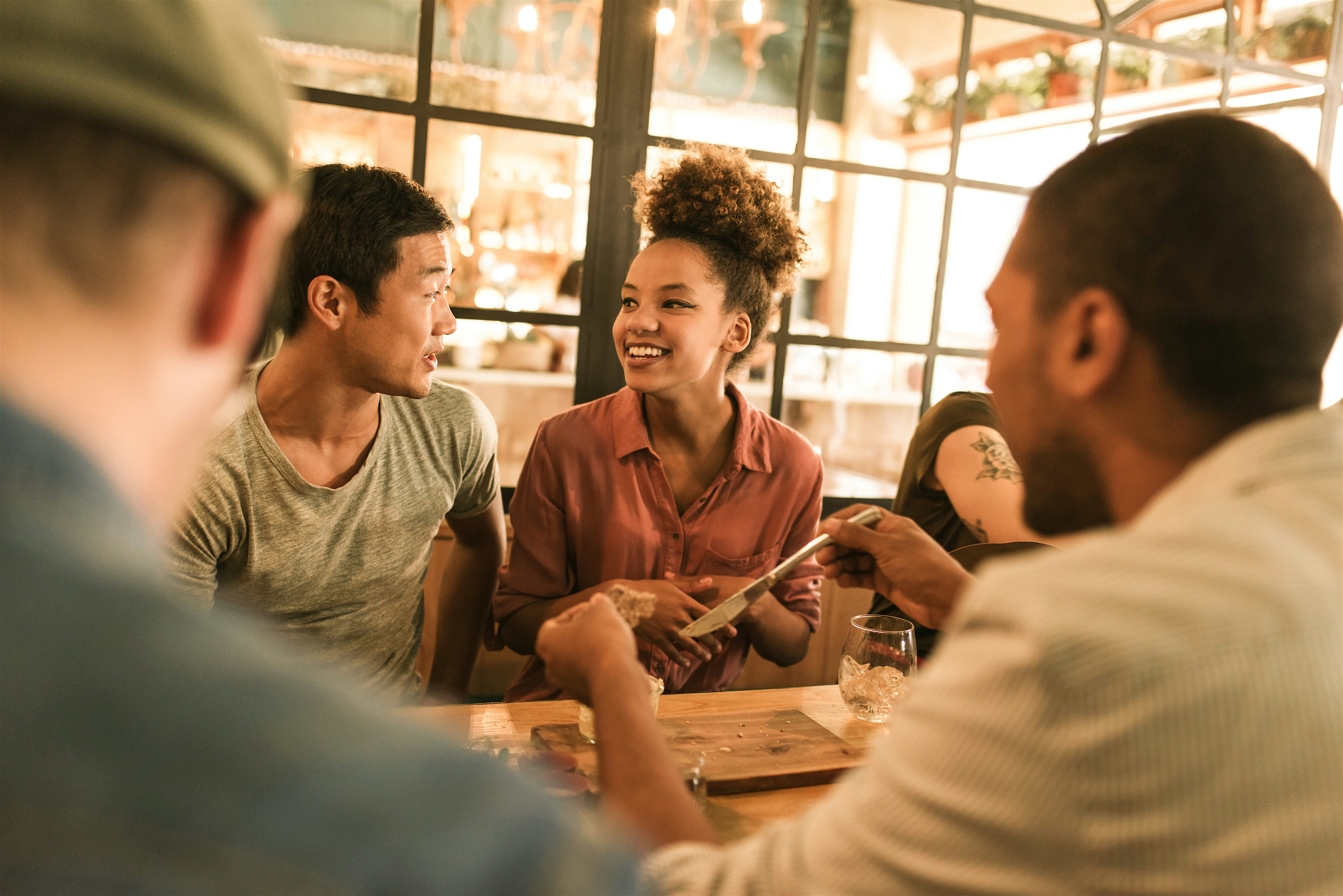 People sitting around a table in a café or bar, chatting with drinks on the table in a relaxed indoor setting