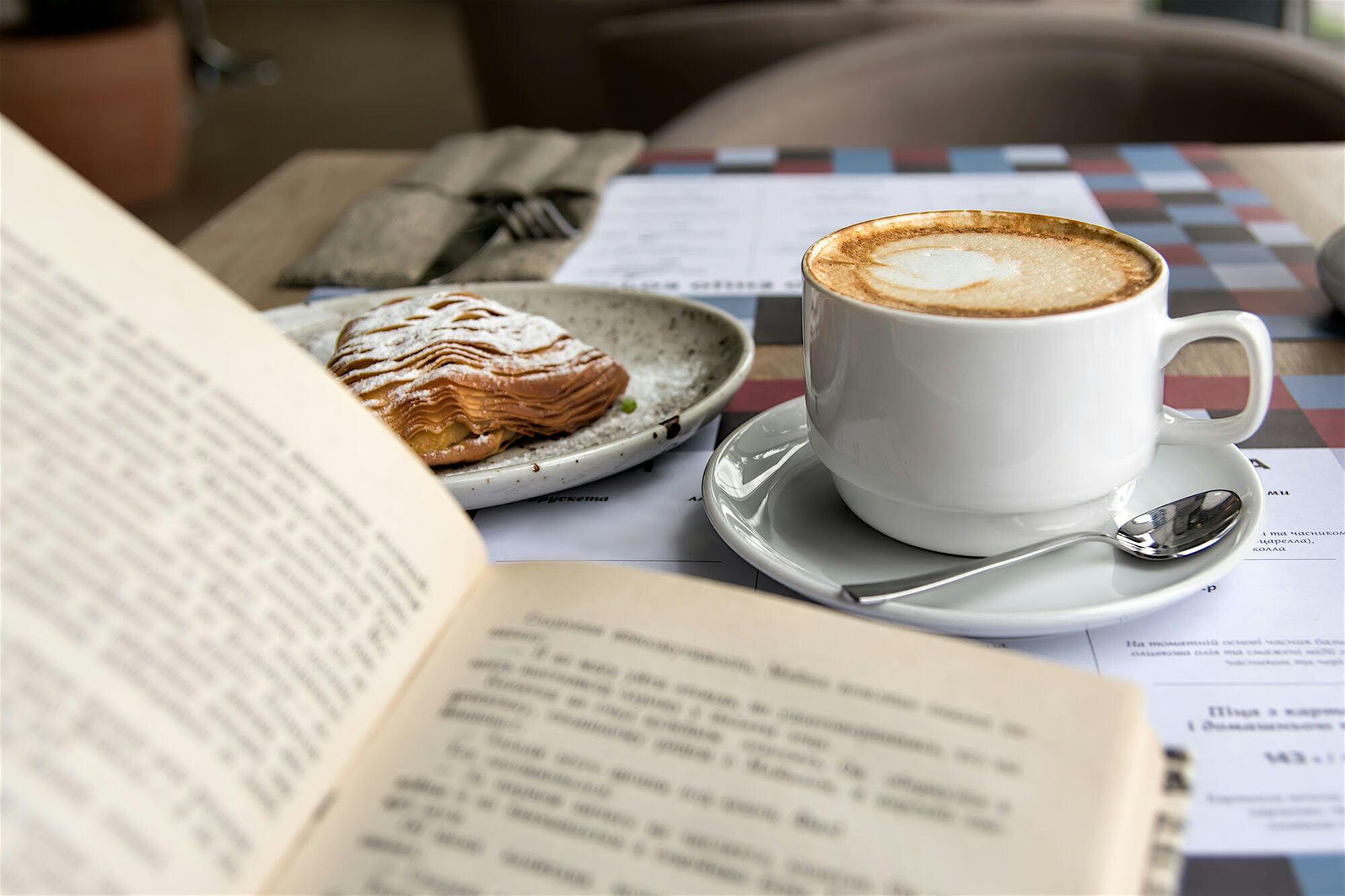 A book and a pastry with a coffee next to it