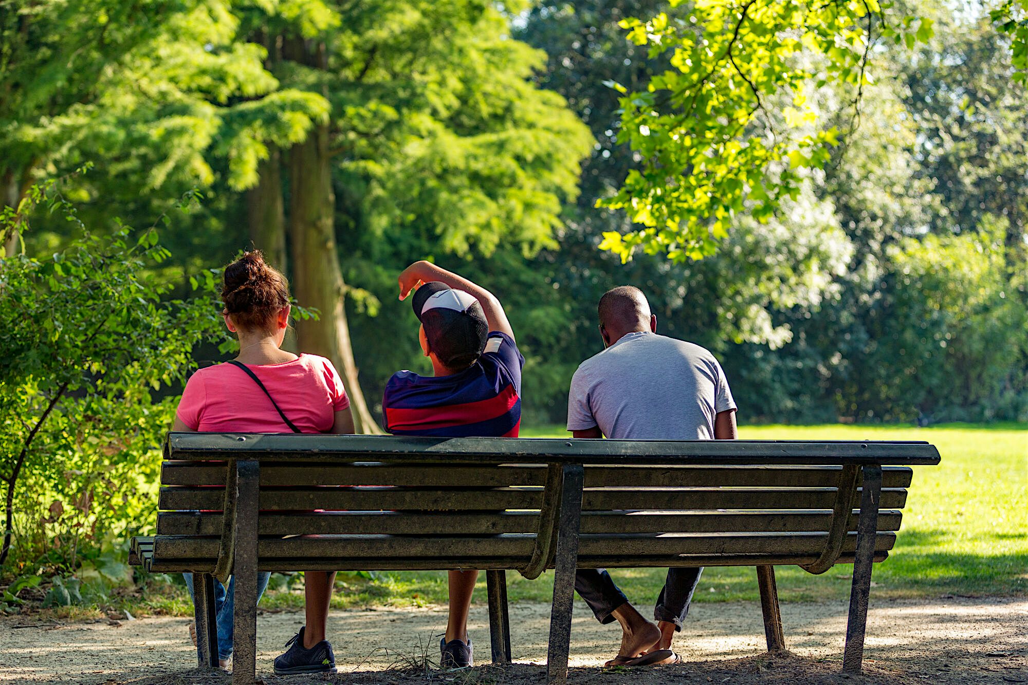 Family of 3 sat on a bench in the park