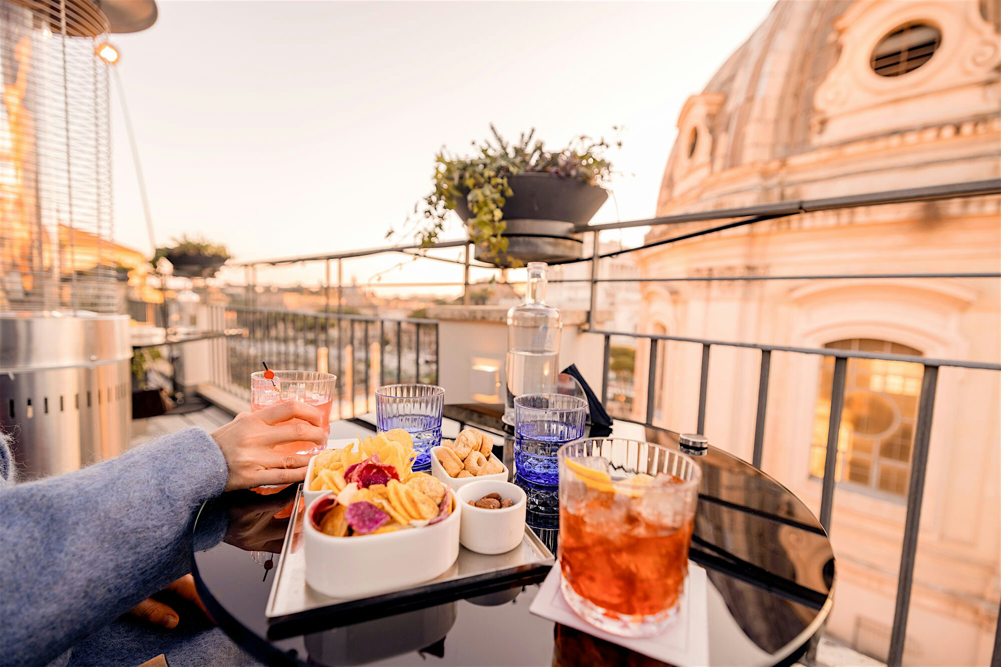 Rooftop restaurant with drinks, and a selection of snacks, a view of the old city and a blue sky