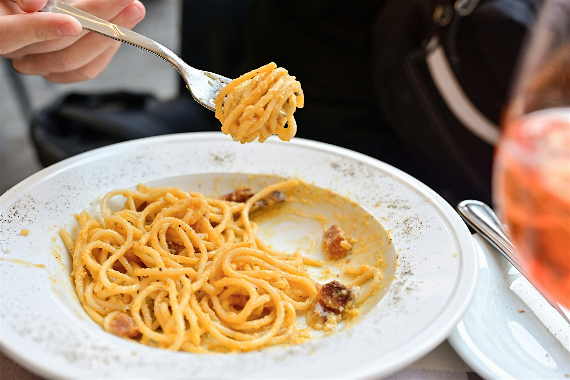 Fresh 'Cacio e pepe' pasta dish (pasta, percorino cheese, and black pepper). A fork is coming out of the dish with pasta twirled around it