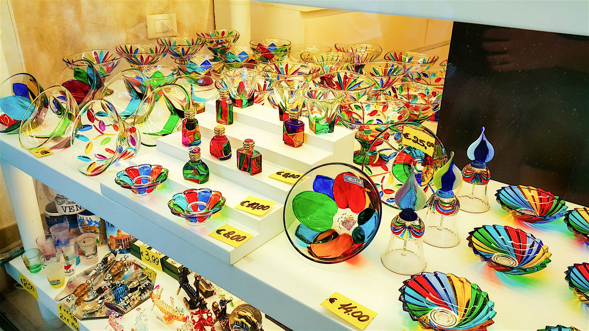 A local shop window with Murano glass, a range of dishes, glass ware and decorations in multicoloured designs and patterns