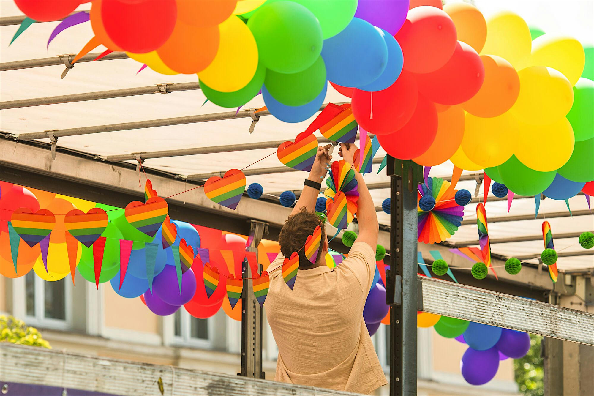 Person hanging rainbow bunting and balloons