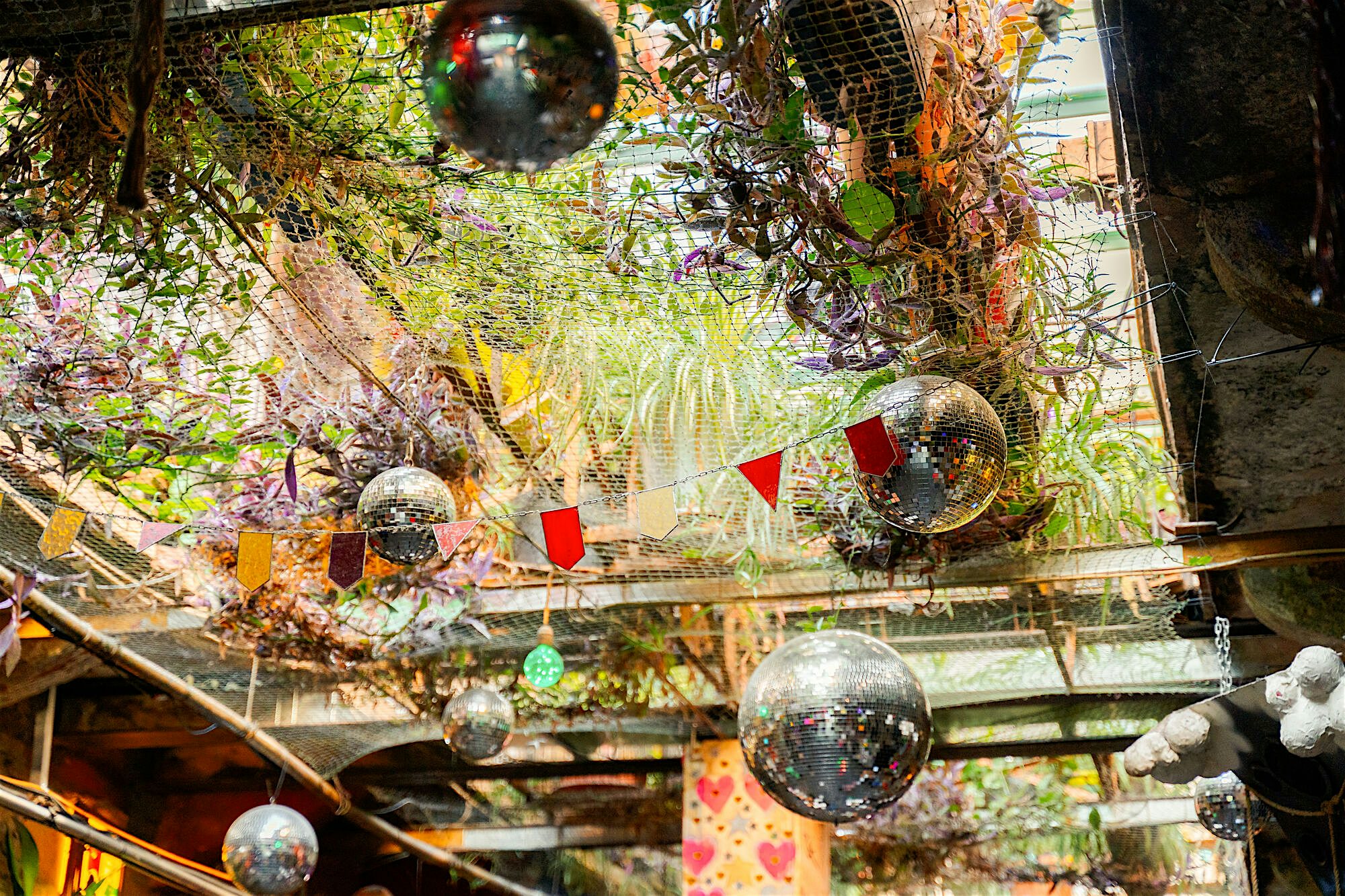 Open‑air courtyard decorated with hanging plants, mirrored disco balls, and colourful bunting