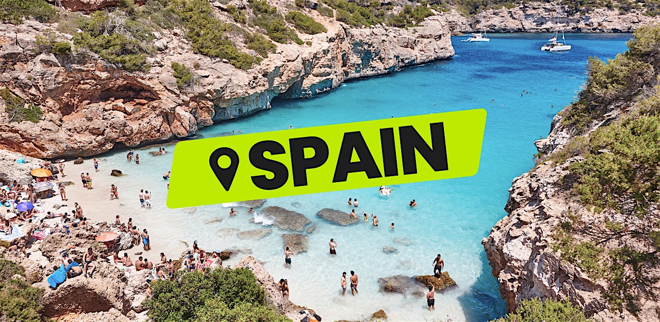 Spain all inclusive beach holiday in rocky cove with clear blue water and people swimming