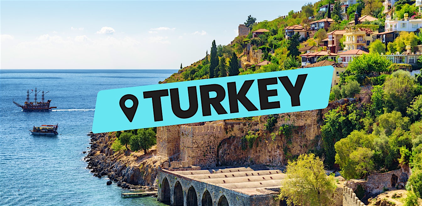 Turkey all inclusive beach holiday with coastal town, historic walls and boats on the sea