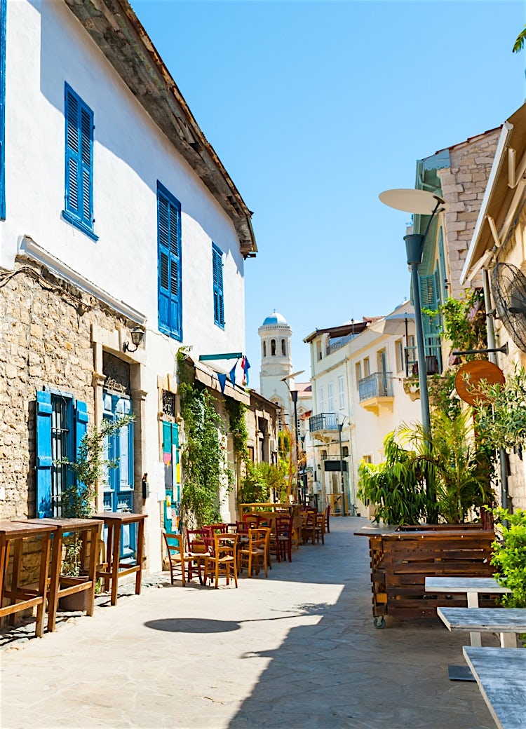 Historic street in Nicosia, Cyprus, with traditional stone buildings, blue shutters, outdoor cafés, and Mediterranean architecture.