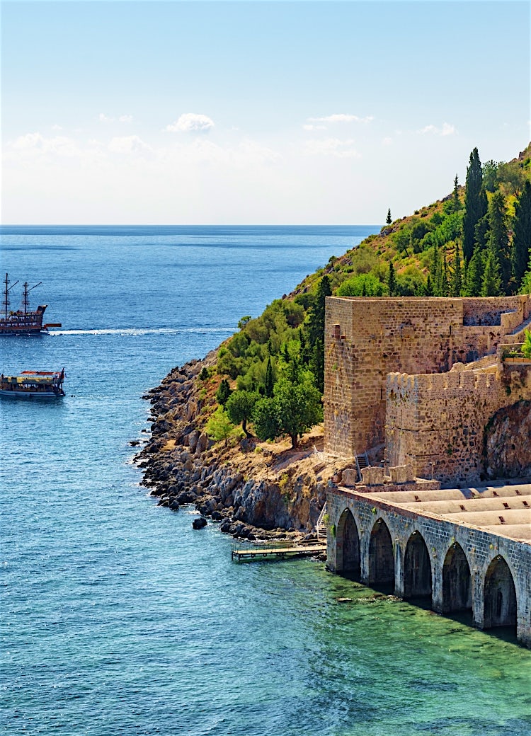 Turkey coastal fortress overlooking turquoise Mediterranean waters, historic stone walls, rocky shoreline and scenic sea views.