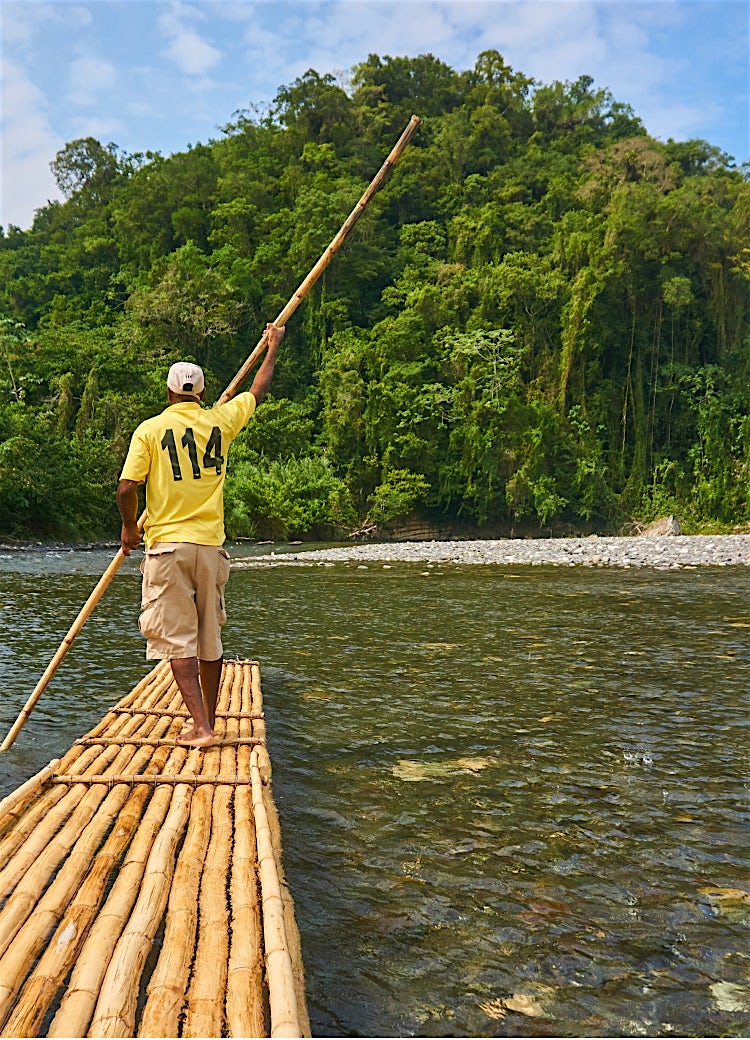 Jamaica bamboo rafting on a tropical river surrounded by lush rainforest and scenic island landscape.