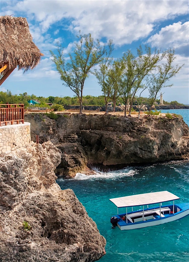 Jamaica rocky coastline with turquoise Caribbean waters, scenic sea cliffs and coastal boat.