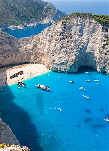Zante Shipwreck Beach with turquoise Ionian waters, dramatic limestone cliffs, white sand cove and boats in Navagio Bay.