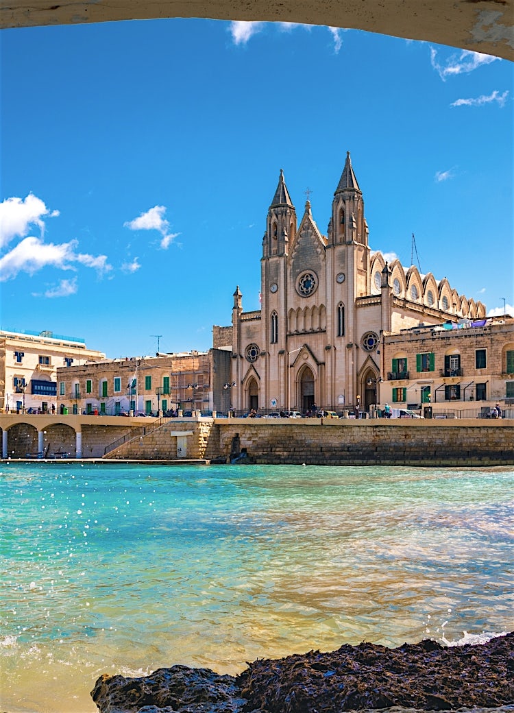 Malta waterfront with historic church, turquoise bay, traditional limestone architecture and scenic Mediterranean harbour views.