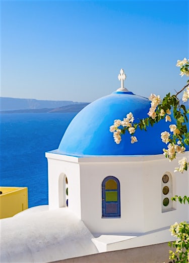 Santorini blue-domed church overlooking the Aegean Sea, whitewashed architecture and iconic Greek island scenery.