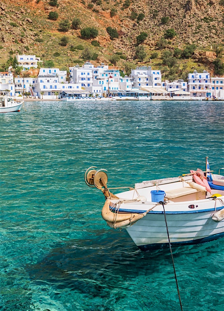 Traditional fishing boats in a Cretan harbour, Greece, with crystal-clear turquoise water and whitewashed coastal village waterfront.