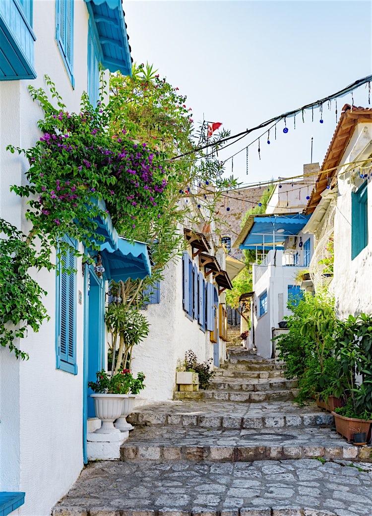 Charming old town street in Marmaris, Turkey, featuring whitewashed houses, blue shutters, vibrant bougainvillea and traditional Mediterranean architecture.