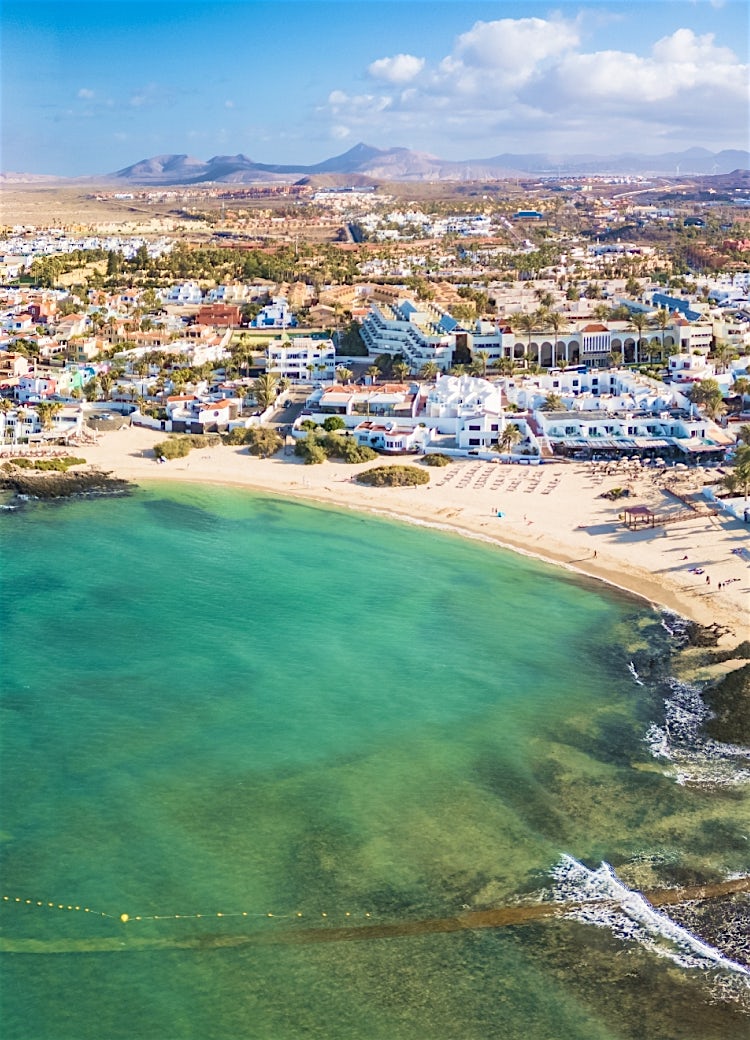 Fuerteventura aerial view featuring turquoise bays, sandy beaches, coastal resorts and dramatic volcanic island landscape.