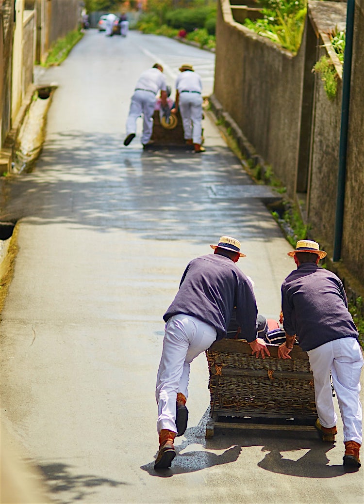 Traditional Madeira wicker toboggan ride in Funchal, with Carreiros guiding wicker sleds down a historic island street.