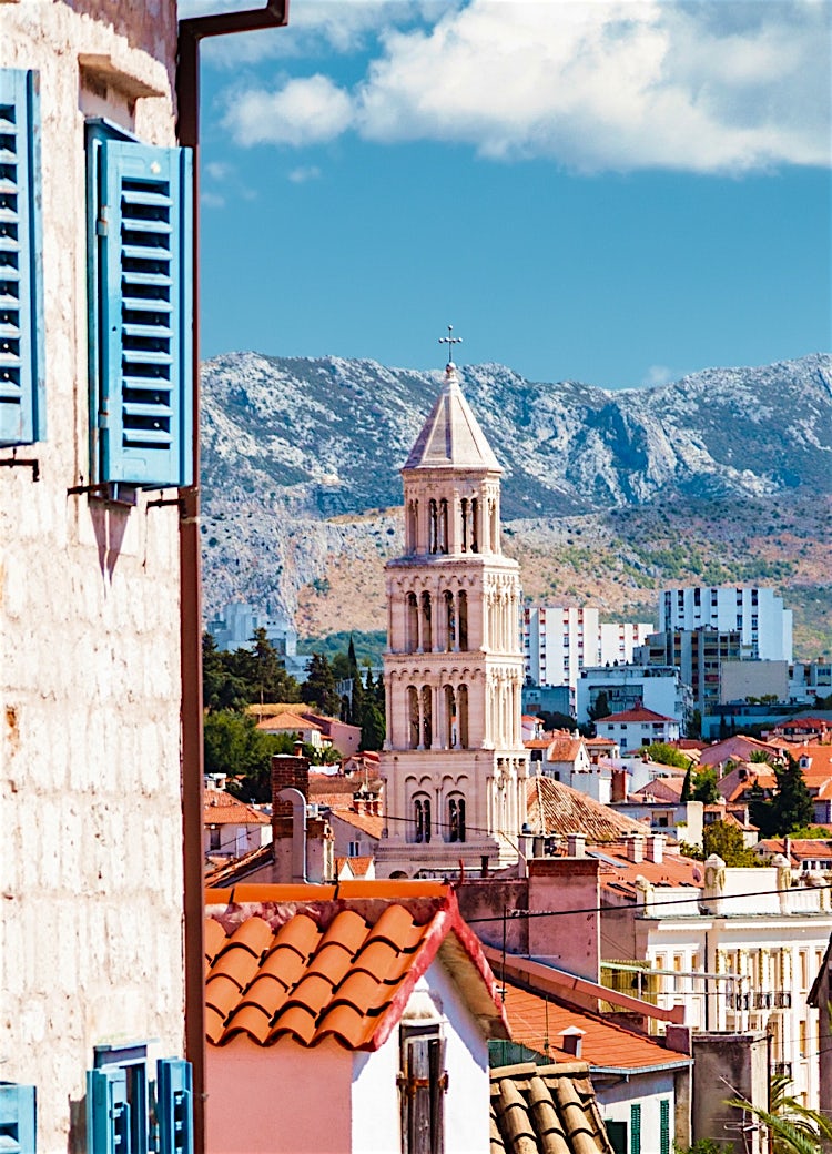 Historic Split, Croatia cityscape featuring Saint Domnius Bell Tower, terracotta rooftops, and mountain views framed by traditional stone buildings.