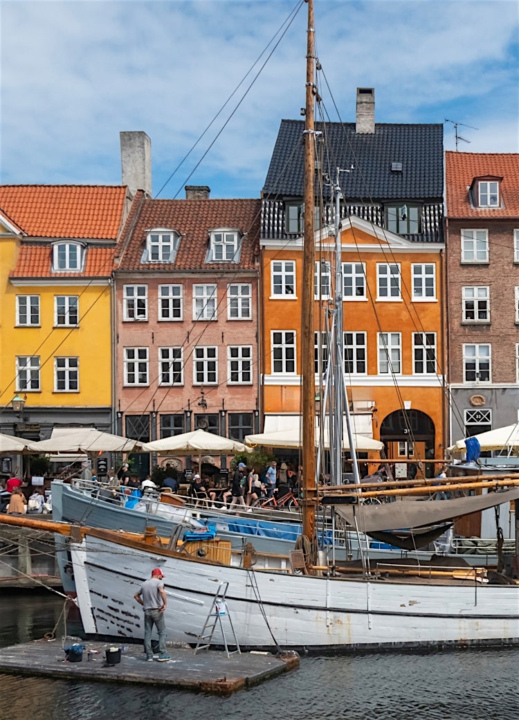 Copenhagen, Denmark. Nyhavn waterfront, colourful buliding facades and old ships along the canal.