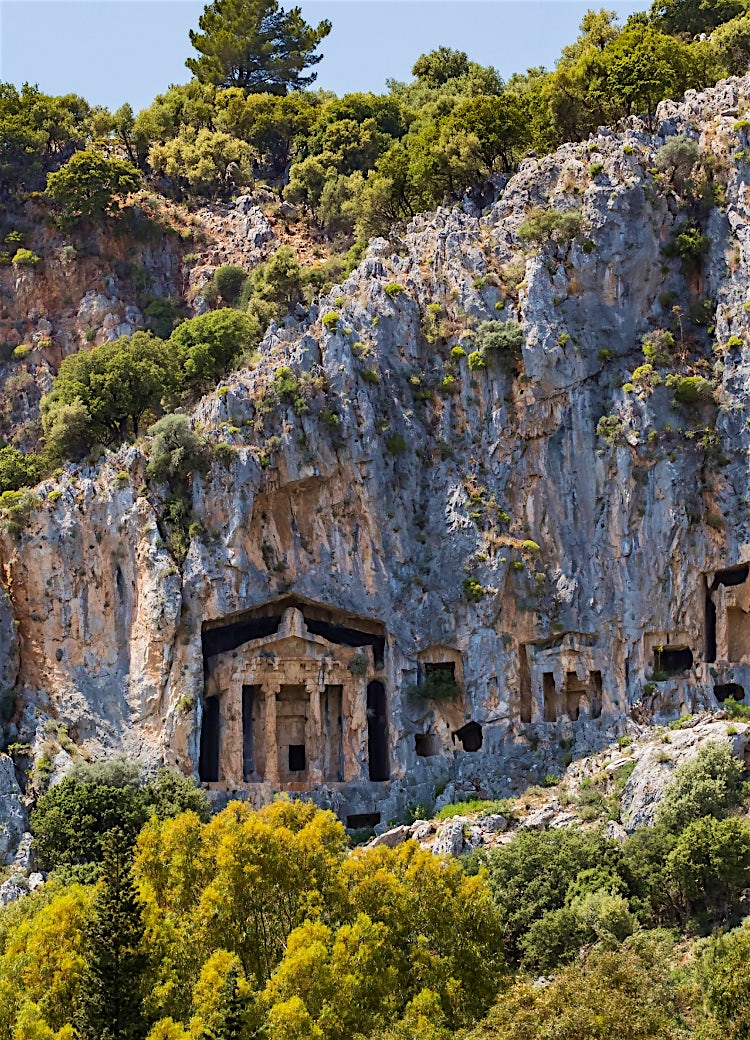 Lycian rock tombs near Dalyan, Turkey, carved into dramatic cliff faces amid rugged mountains and historic ancient ruins.