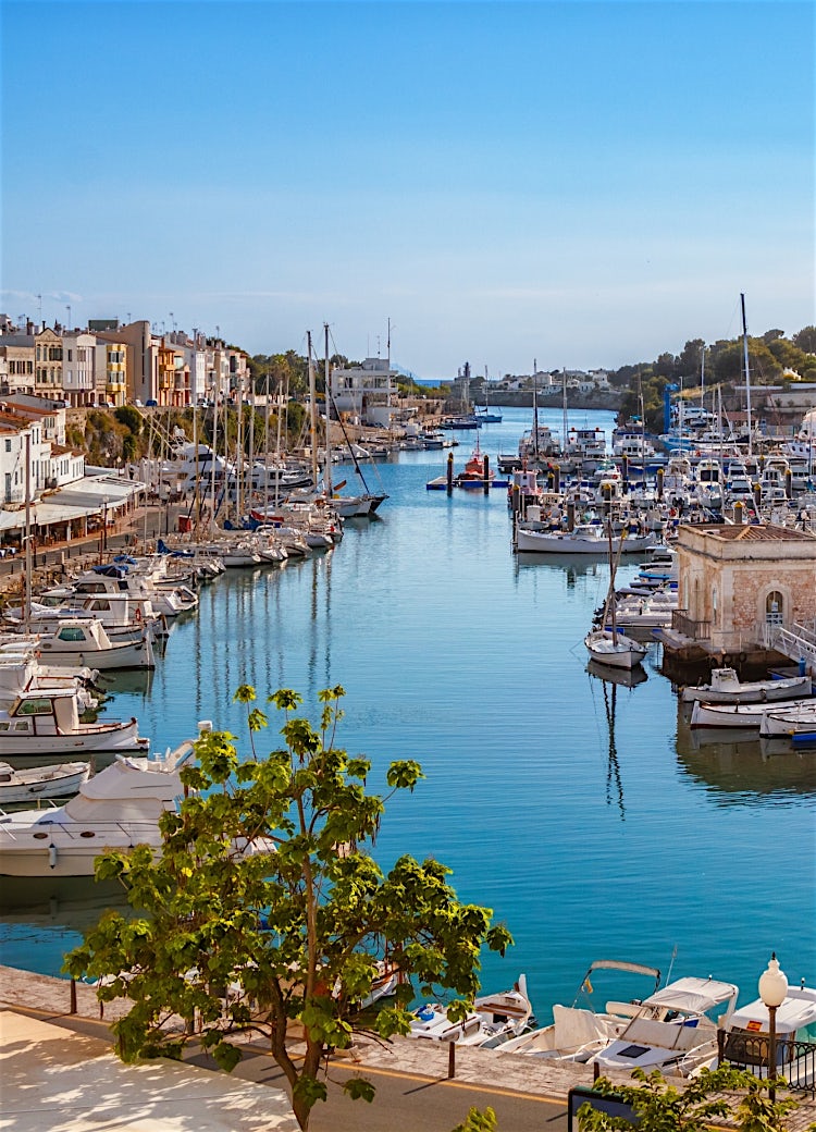 Ciutadella Harbour in Menorca, Balearic Islands, with luxury yachts, waterfront promenade, historic architecture, and scenic Mediterranean marina views.