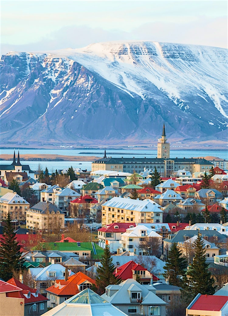 Reykjavik, Iceland, city skyline with colourful rooftops, Hallgrímskirkja church, snow-capped mountains, and scenic coastal views.
