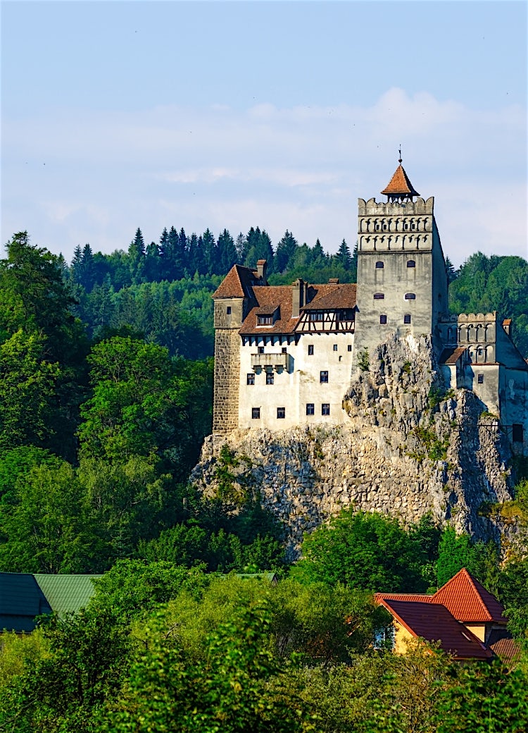 Bran Castle, Romania, perched on a rocky hilltop and surrounded by dense Transylvanian forest.