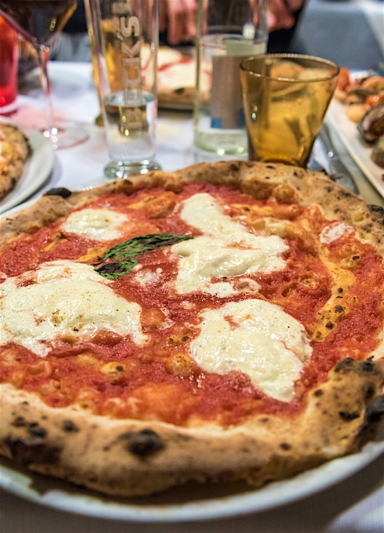 Authentic Neapolitan Margherita pizza in Rome, Italy, topped with mozzarella, tomato sauce, and basil at a traditional restaurant.