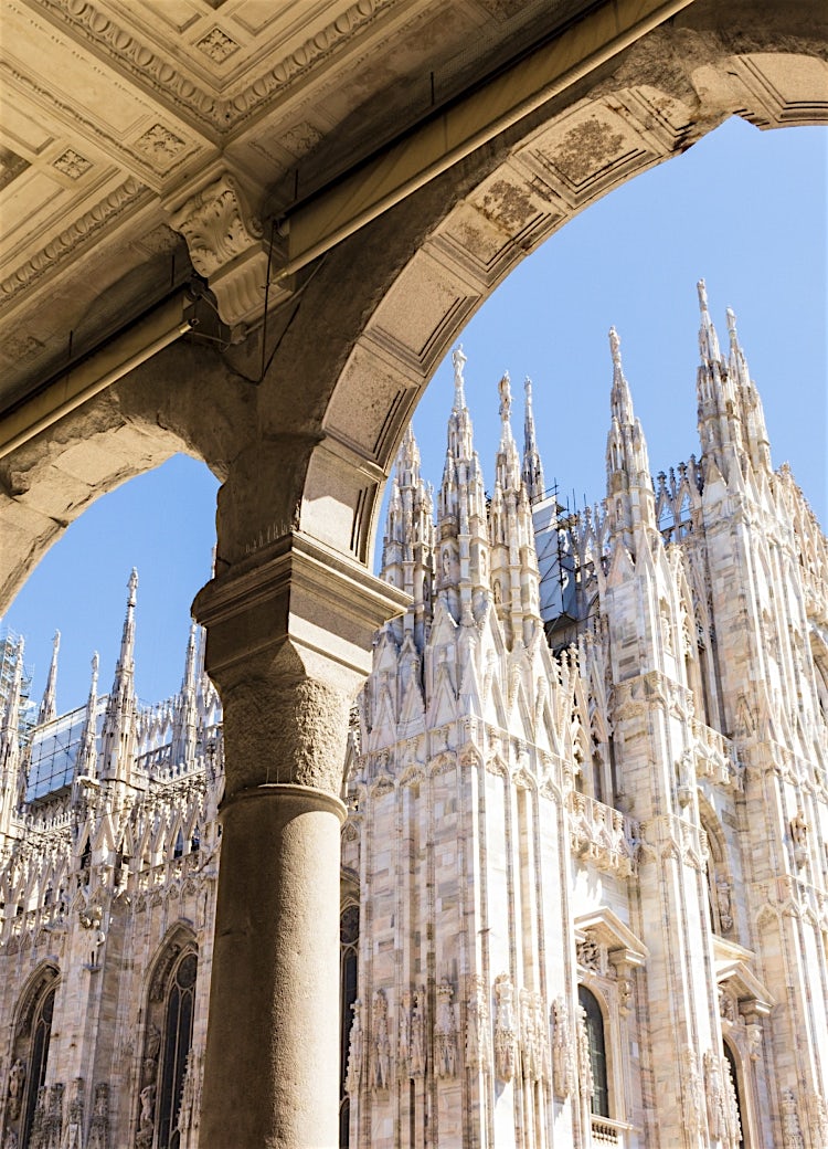 Milan Cathedral (Duomo di Milano) in Milan, Italy, showcasing ornate Gothic architecture, intricate marble spires and historic city landmark arches.