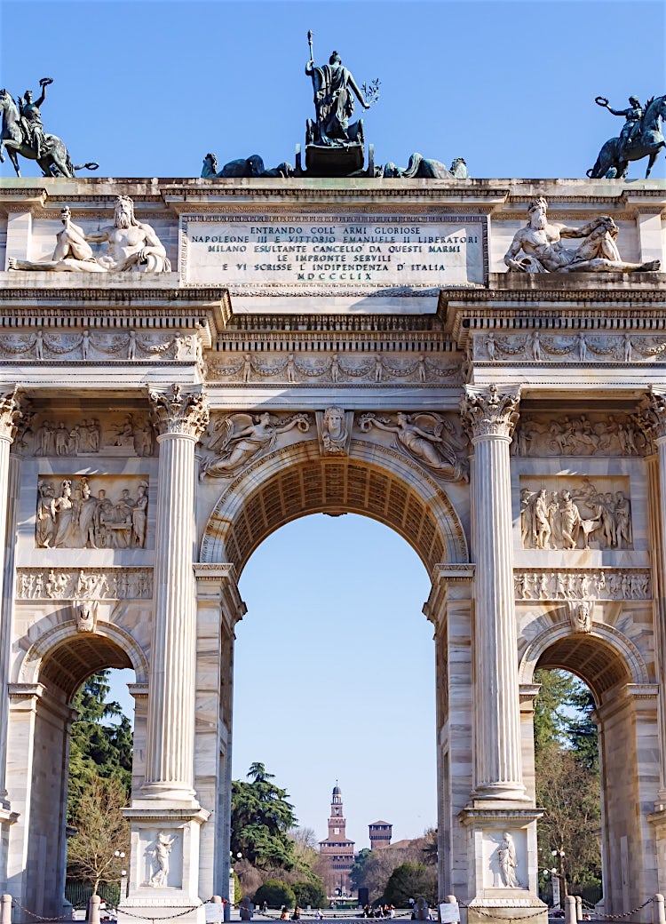 Arco della Pace in Milan, Italy, showcasing the iconic neoclassical triumphal arch, ornate sculptures and historic city landmark against a clear blue sky.