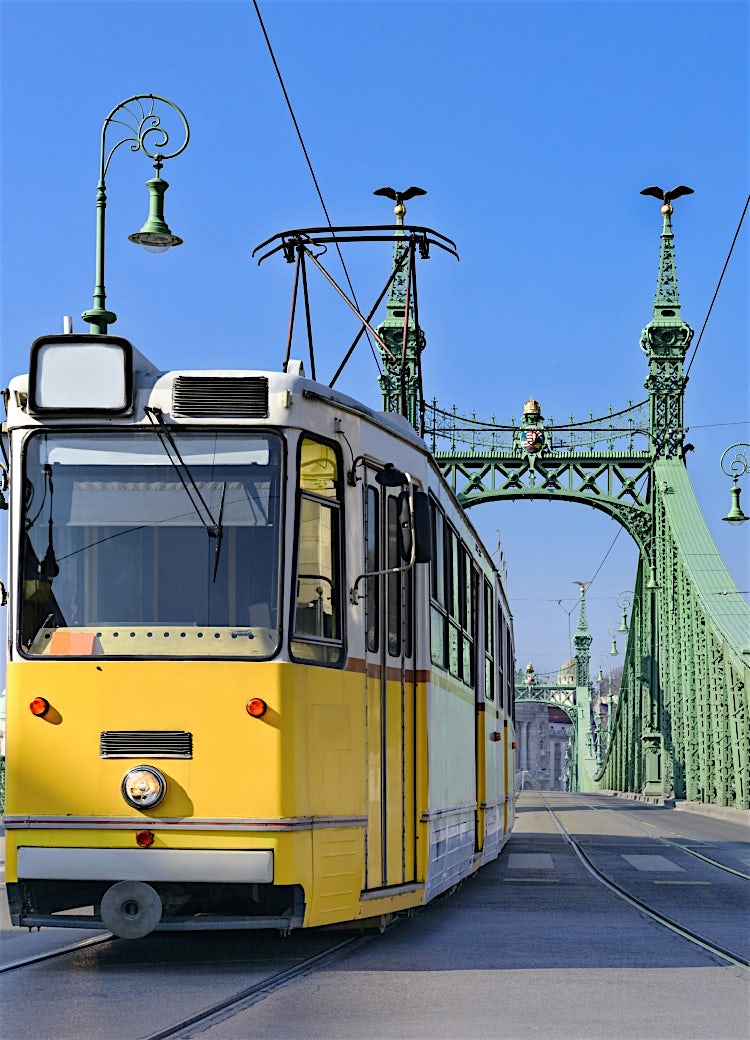Yellow tram crossing Budapest’s Liberty Bridge, Hungary, featuring iconic green steel architecture and a historic Danube River city landmark.